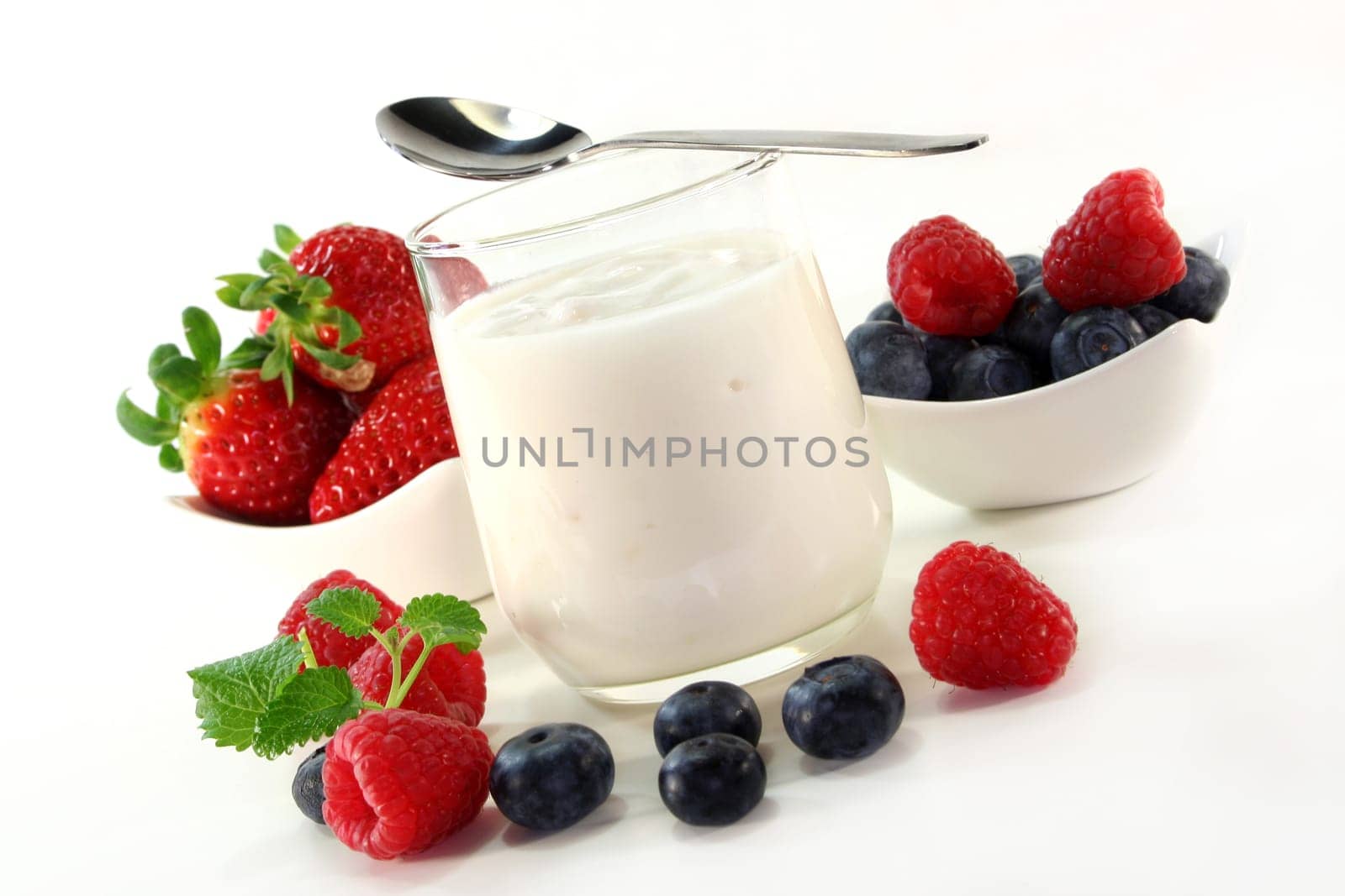 a jar of yogurt and fresh fruits against a white background