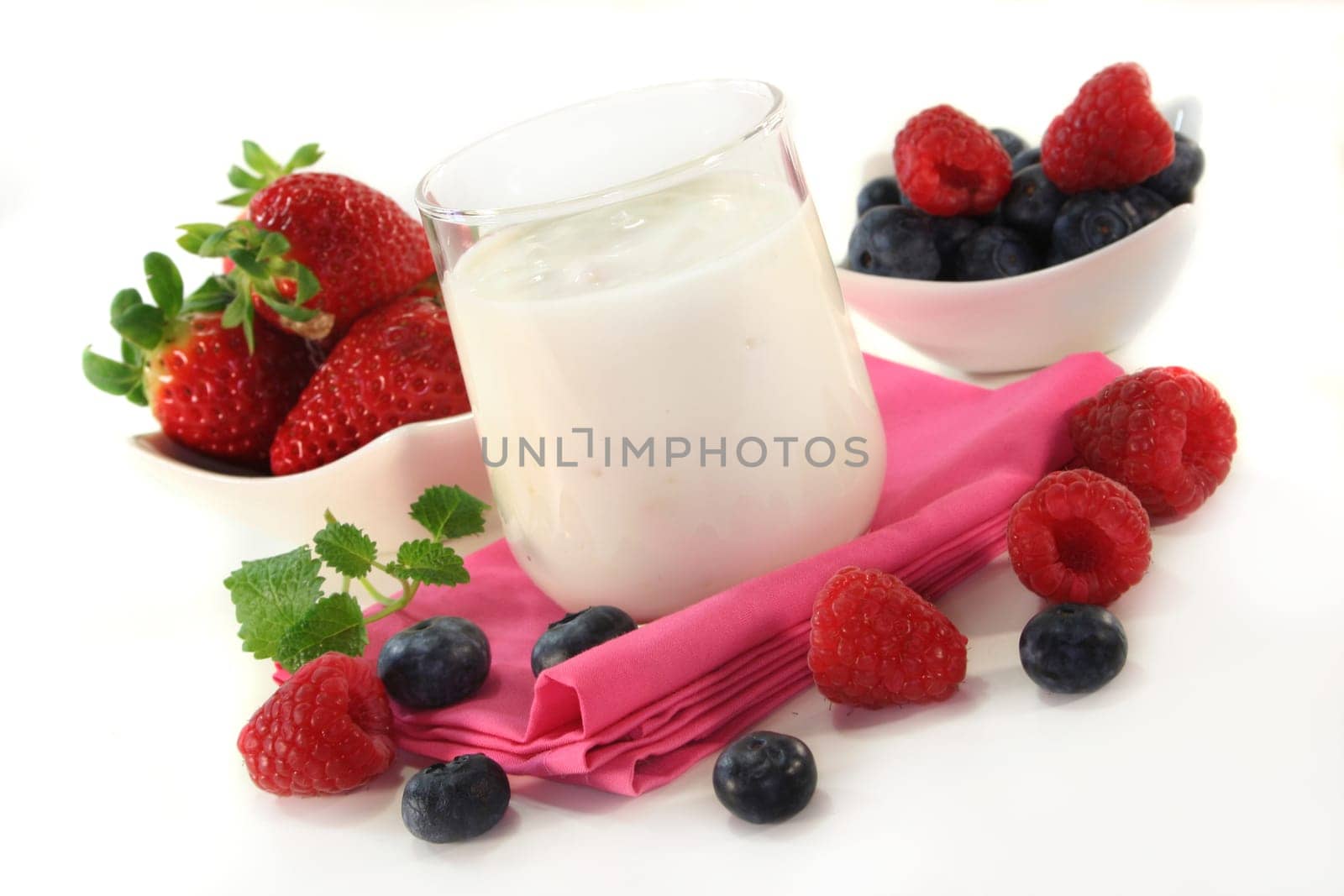 a jar of yogurt and fresh fruits against a white background