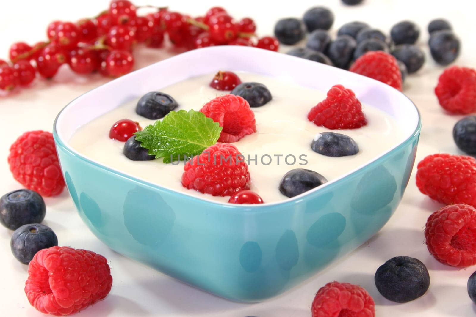 a jar of yogurt and fresh fruits against a white background