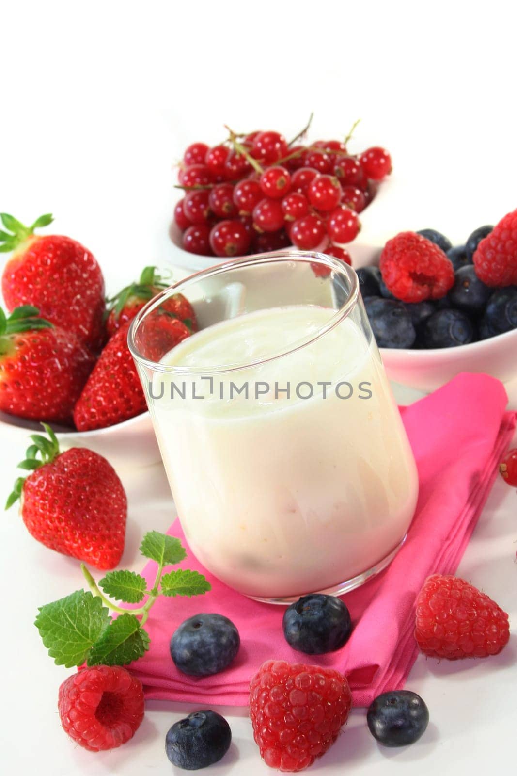 a jar of yogurt and fresh fruits against a white background