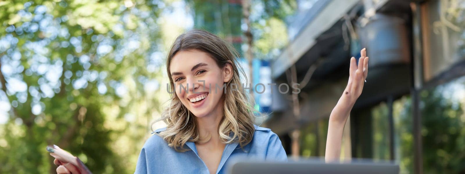 Vertical shot of smiling successful businesswoman, using digital tablet, sitting outdoors in park, working with laptop. Coporate people concept.