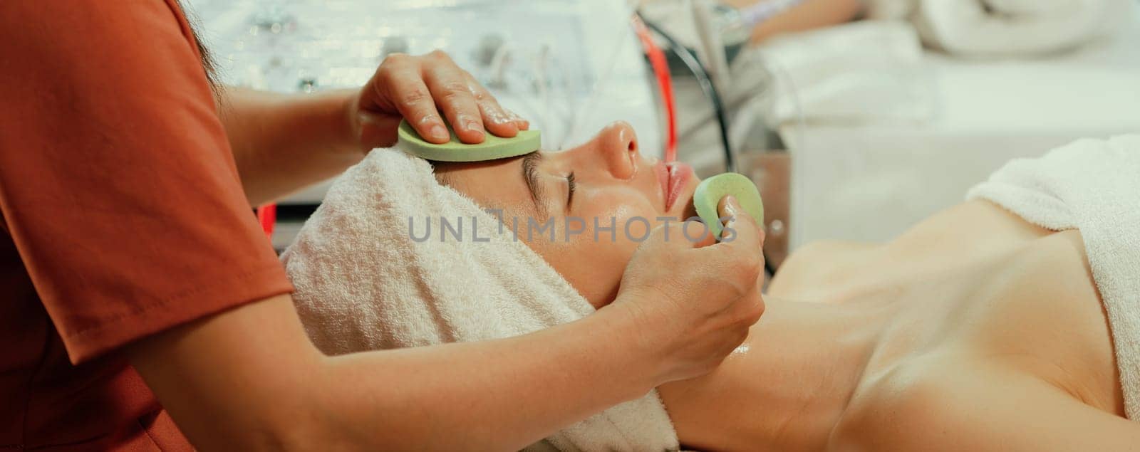 Beautiful young women lie on spa bed while having facial massage from professional doctor. Attractive female with beautiful skin surrounded by electric facial machine. Tranquility.