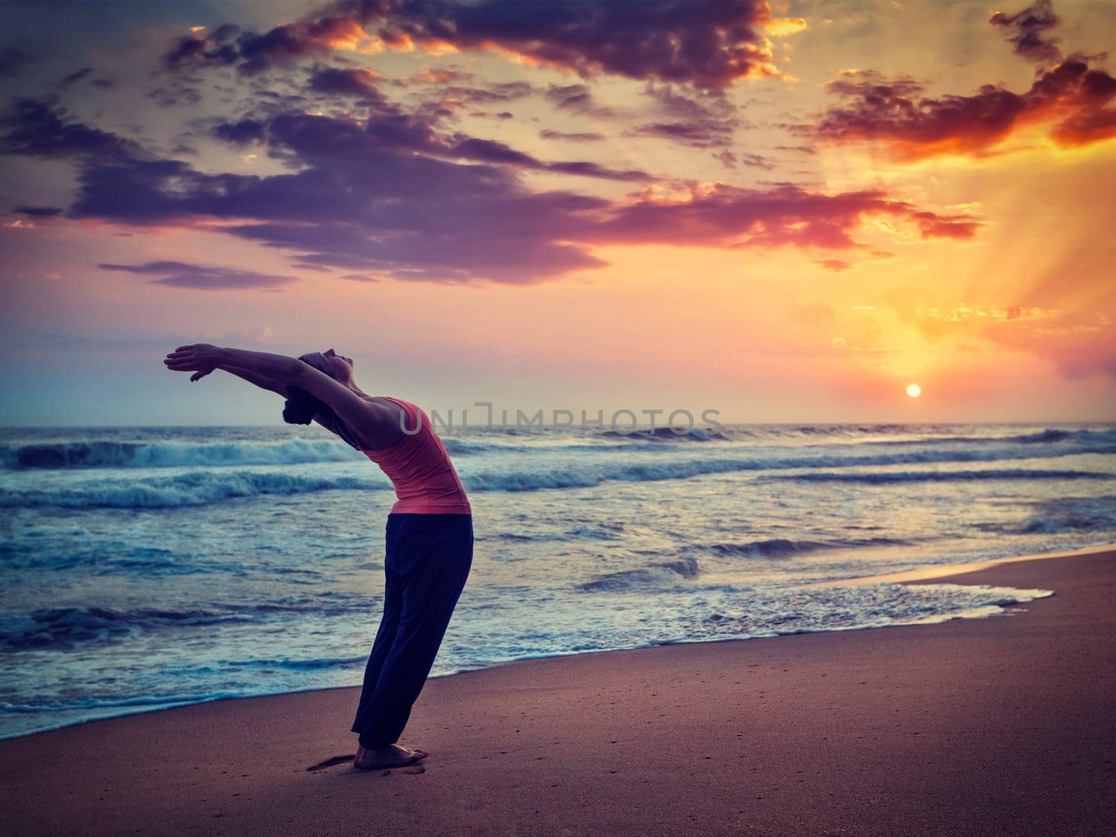 Young sporty fit woman doing yoga Sun salutation Surya Namaskar by dimol