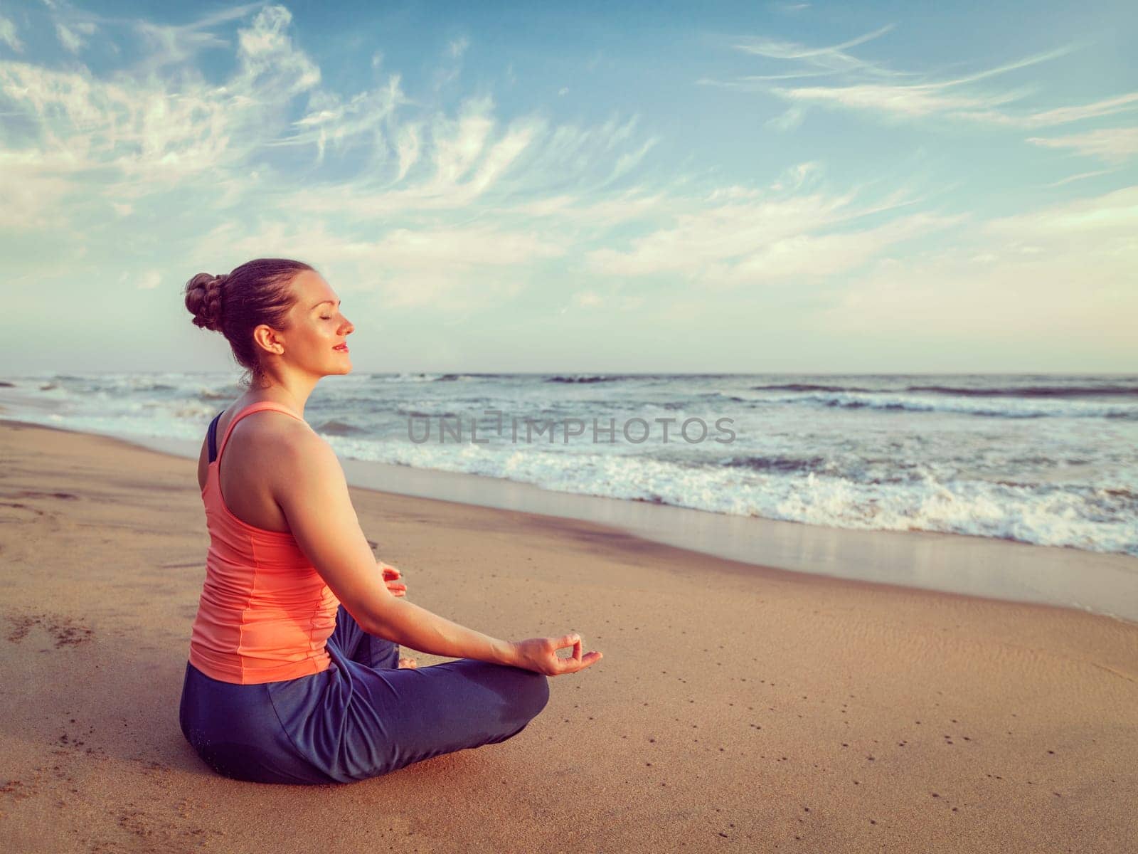Young sporty fit woman doing yoga oudoors at beach by dimol