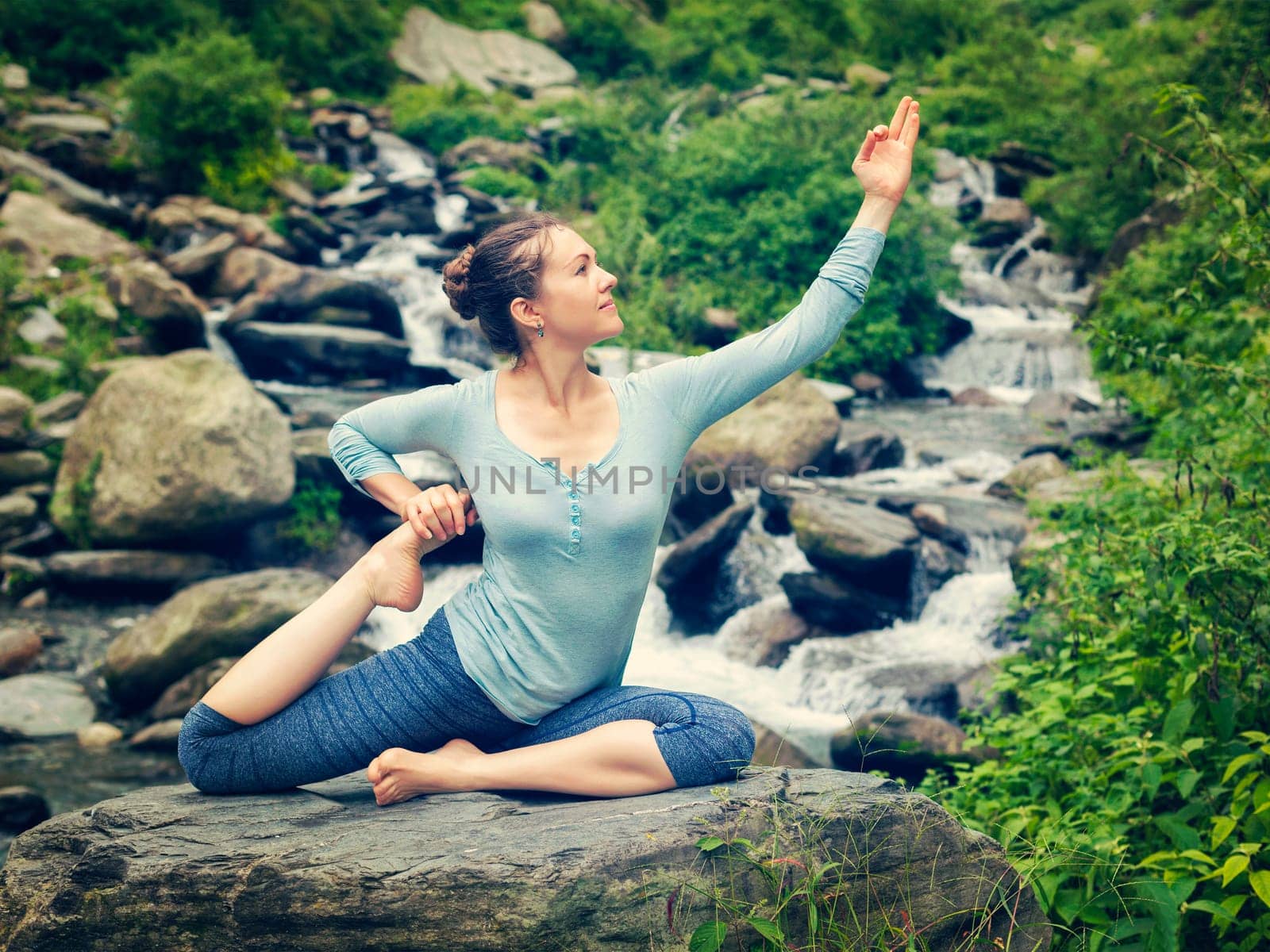 Sorty fit woman doing yoga asana outdoors at tropical waterfall by dimol