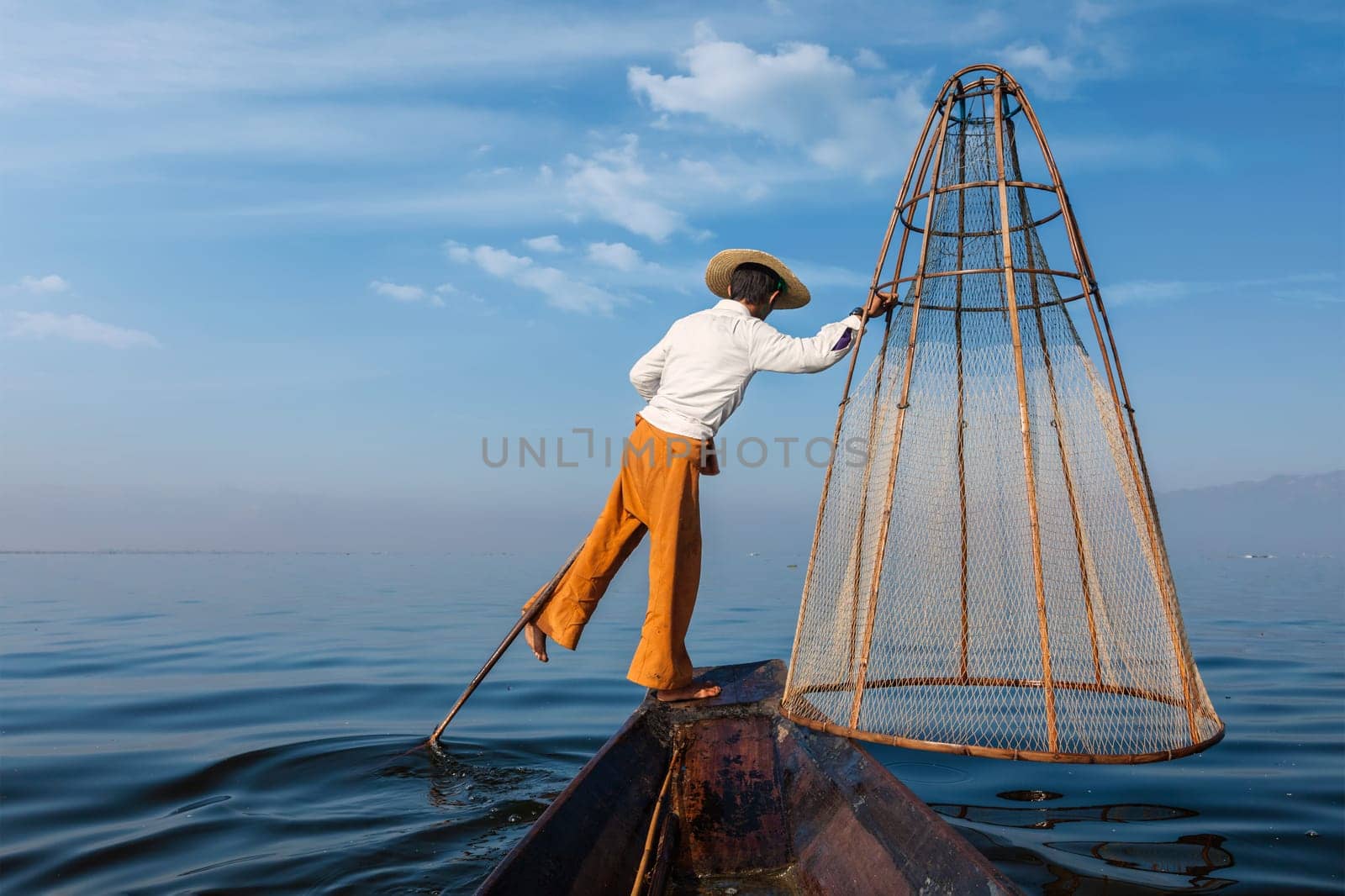 Myanmar travel attraction landmark - Traditional Burmese fisherman with fishing net at Inle lake in Myanmar famous for their distinctive one legged rowing style, view from boat