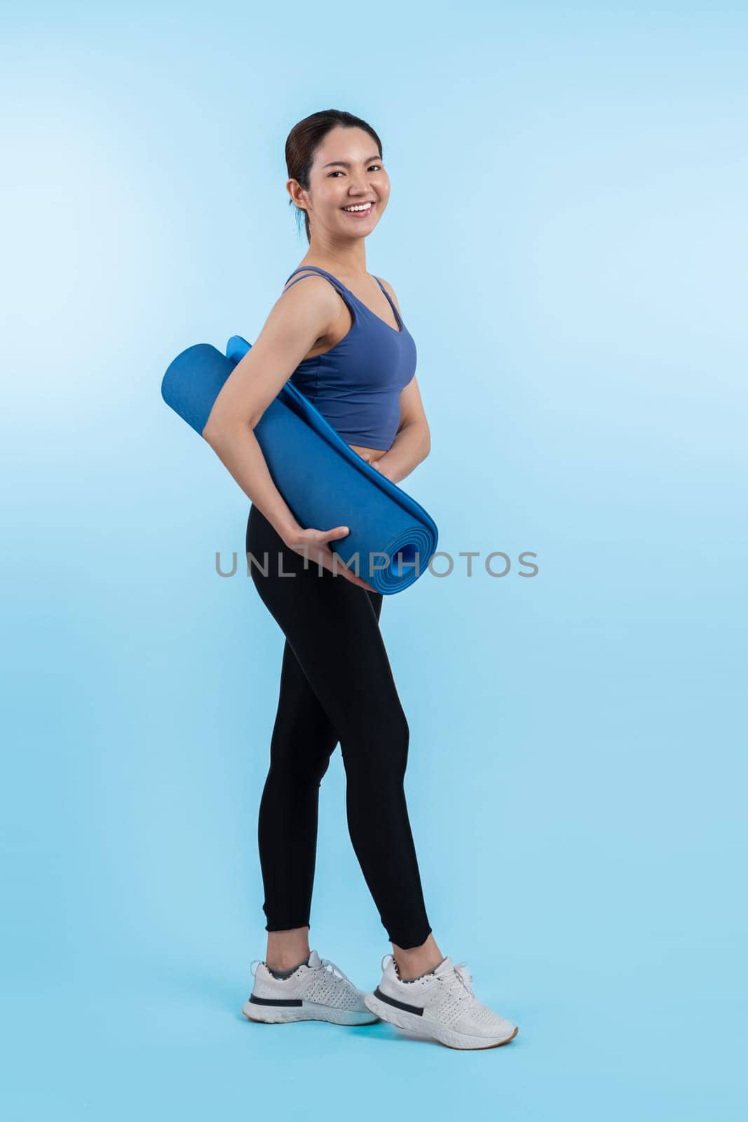 Young attractive asian woman portrait in sportswear with exercising mat. Healthy exercise and workout routine lifestyle concept. Studio shot isolated background. Vigorous