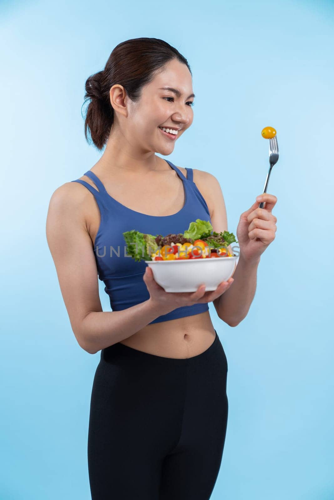 Asian woman in sportswear holding salad bowl on isolated background. Vigorous by biancoblue