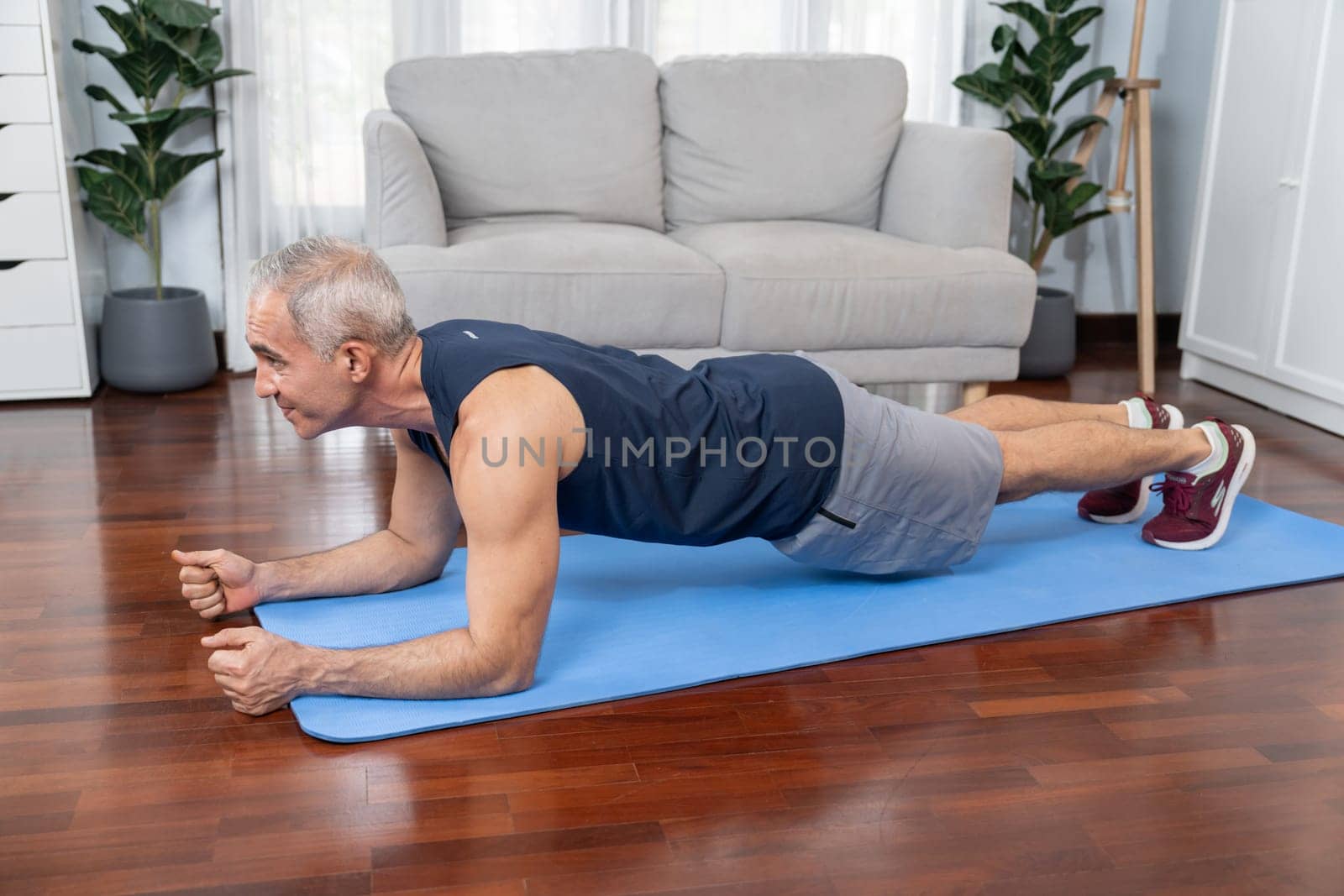 Athletic and sporty senior man planking on fitness exercising mat at home. Clout by biancoblue
