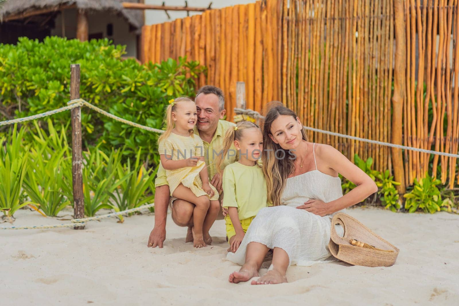 A joyful family, two girls, dad, and a pregnant mom, bask in tropical beach bliss, celebrating a radiant pregnancy amidst paradise by galitskaya
