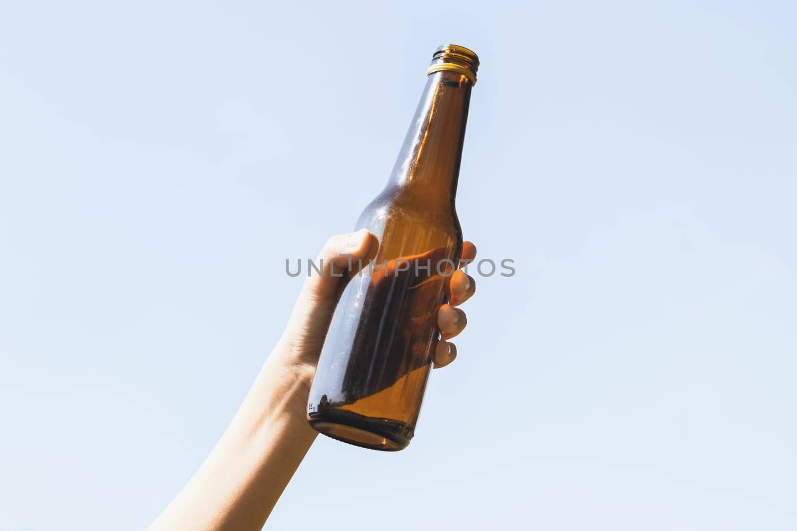 Recyclable glass bottle held in hand up on sky background. Hand holding plastic waste for recycle reduce and reuse concept to promote clean environment with effective recycling management. Gyre