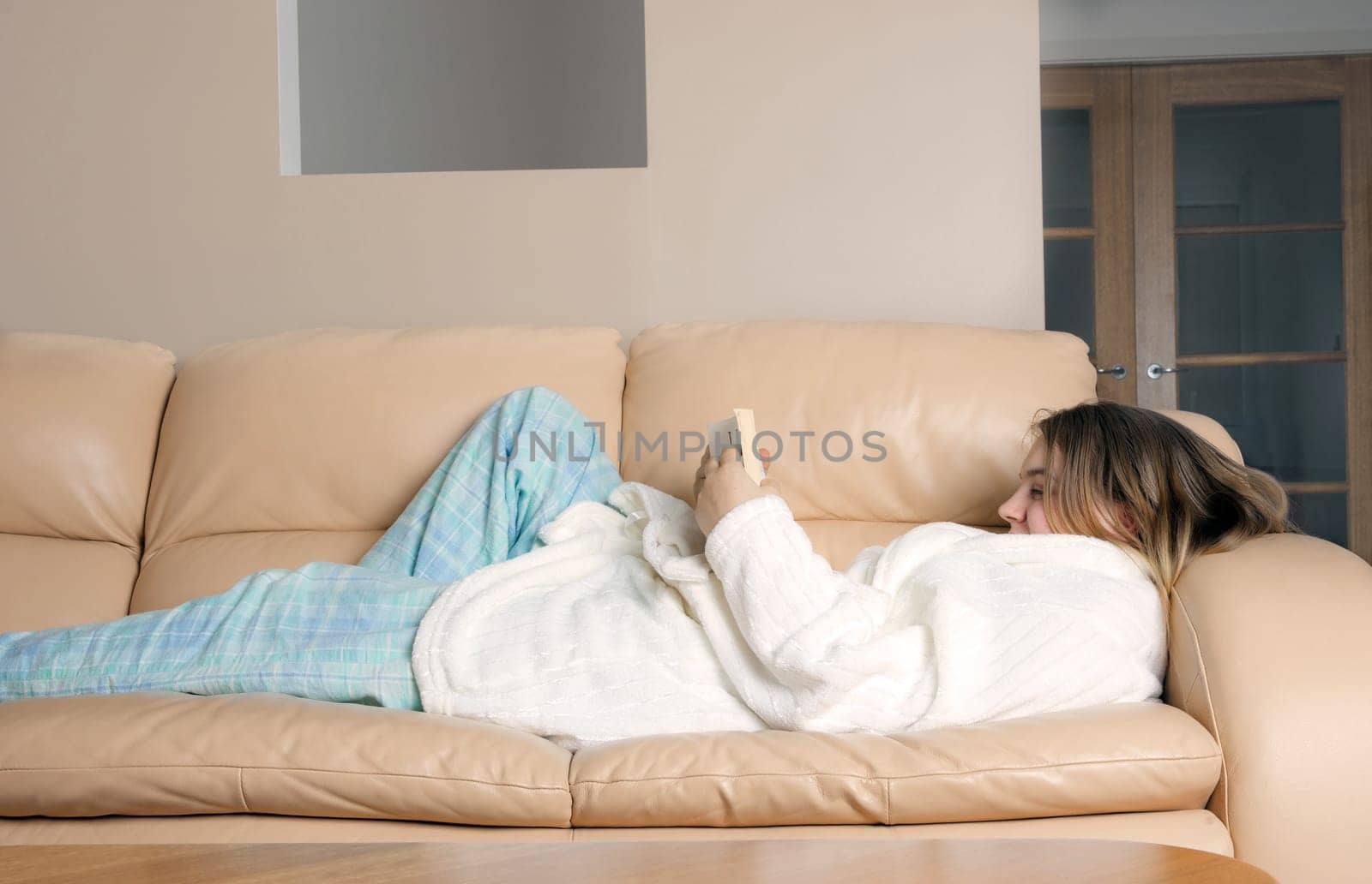 young woman on sofa reading in pajamas