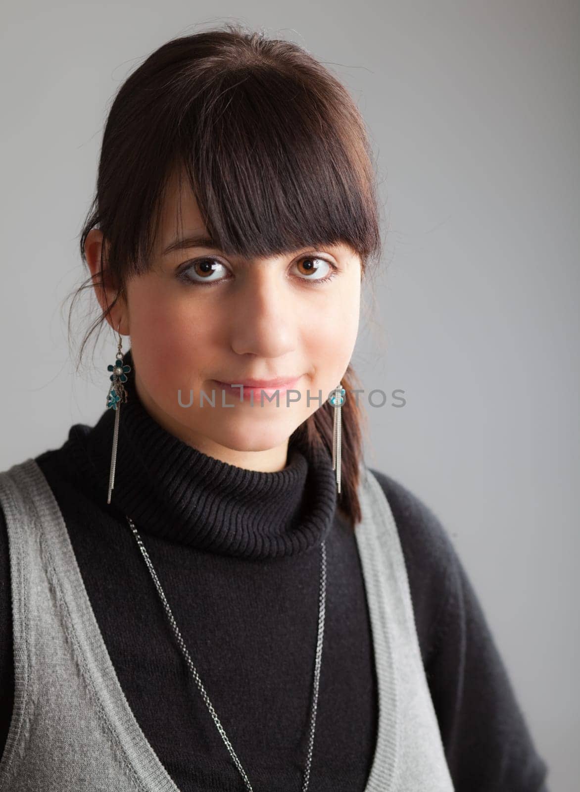 Portrait of a young brunette woman on gray background