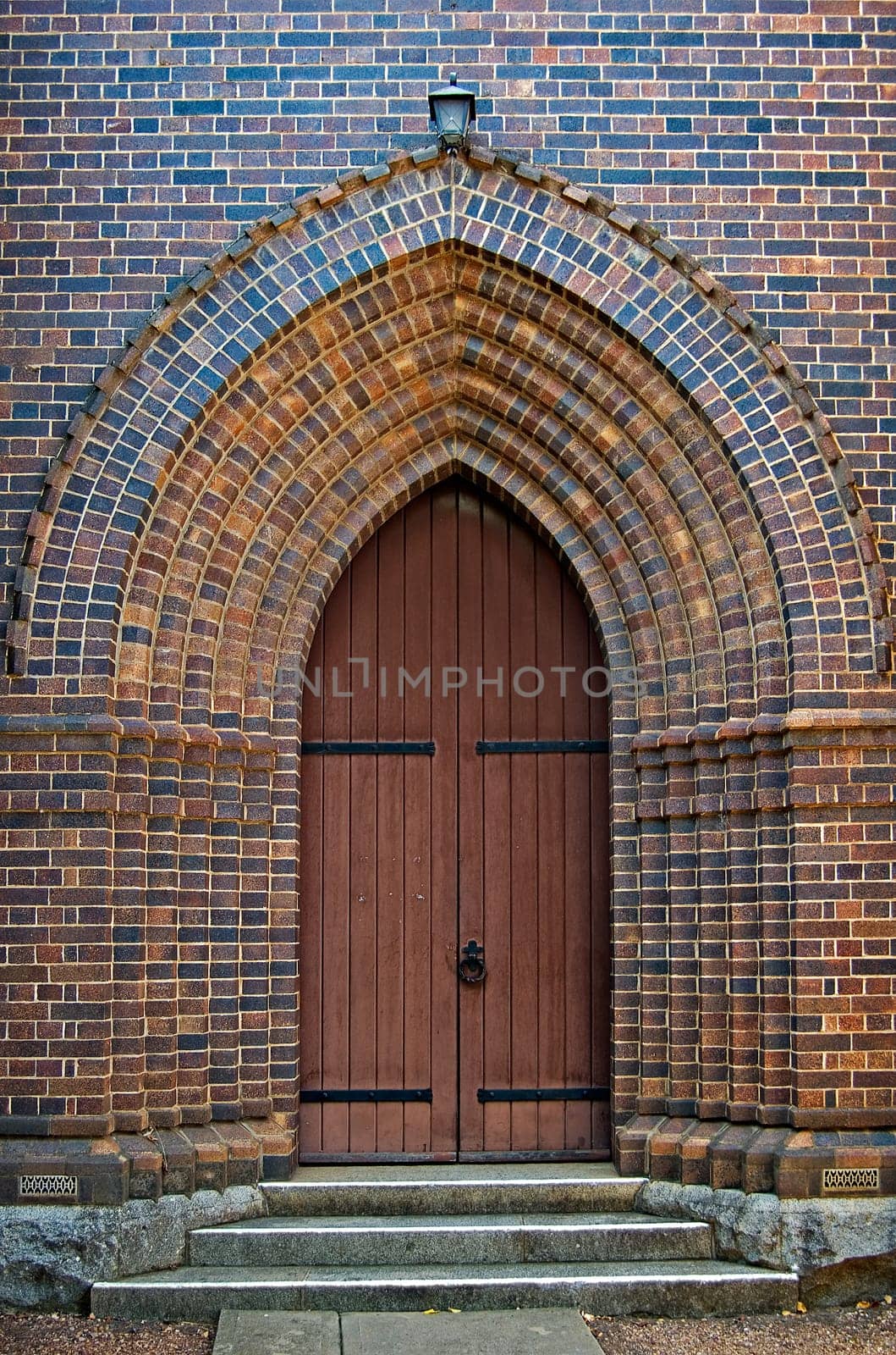 an arched brick doorway with wooden door leading into the church
