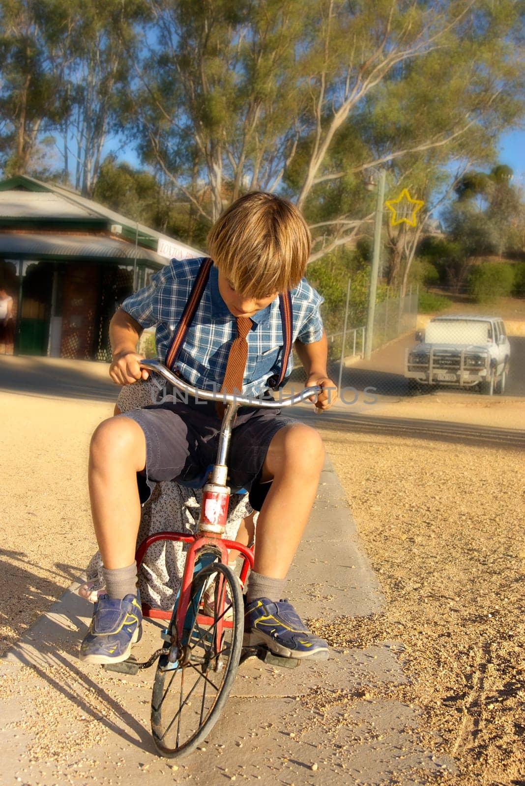 young boy in old style clothing rides a tricycle