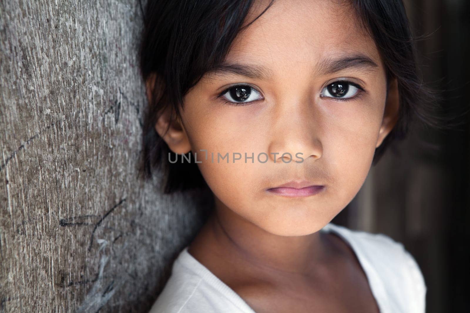 Portrait of a pretty 8 year old Filipina girl in poverty-stricken neighborhood, natural light.