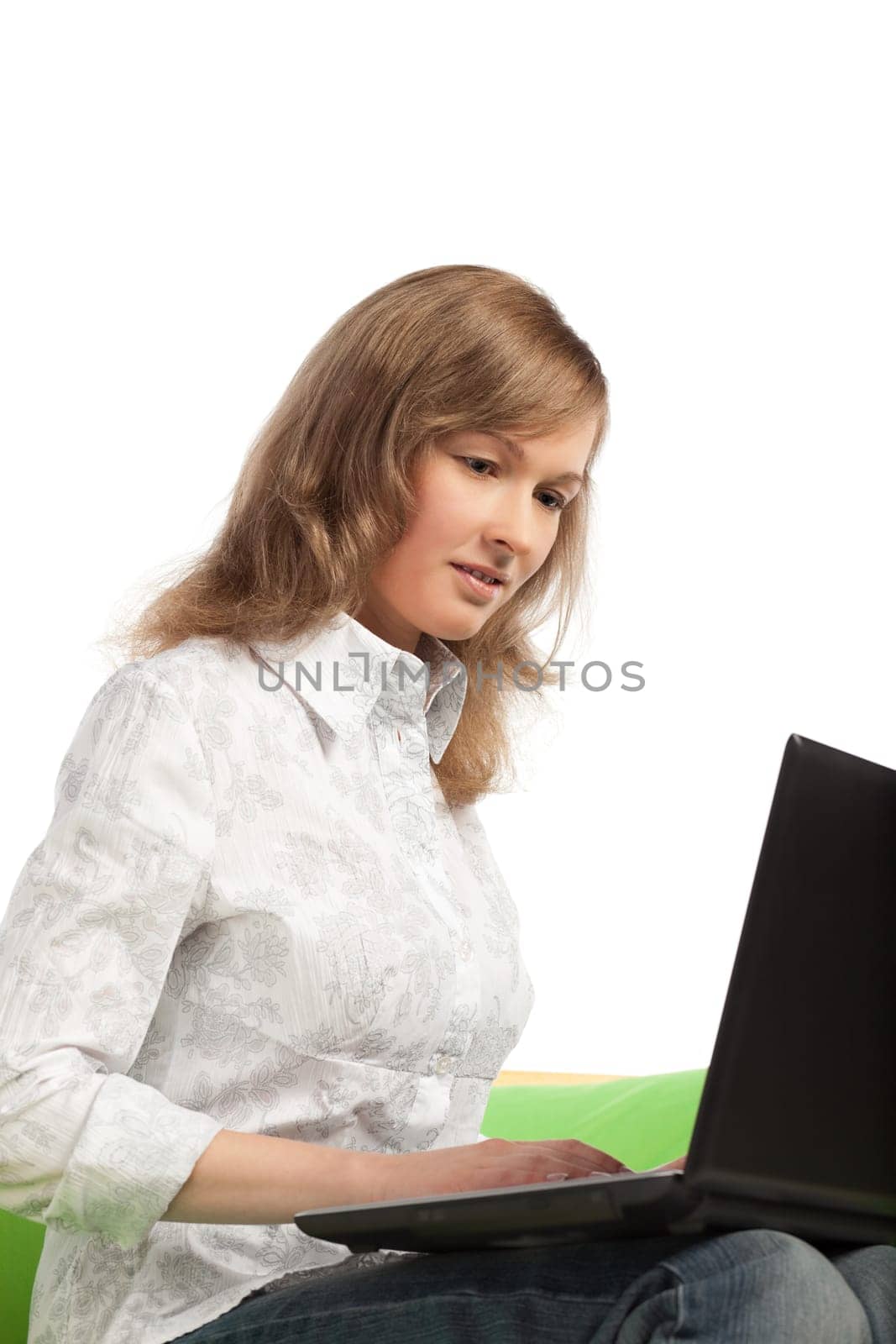 Pretty young blond woman sitting on green sofa with laptop computer