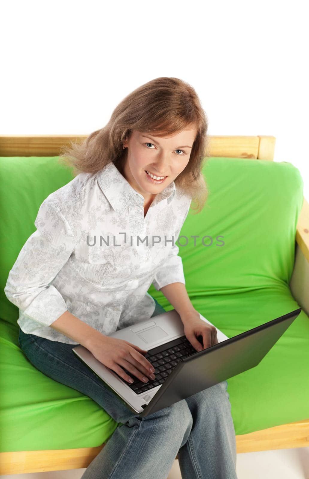 Young blond pretty woman sitting on sofa with laptop computer  isolated on white