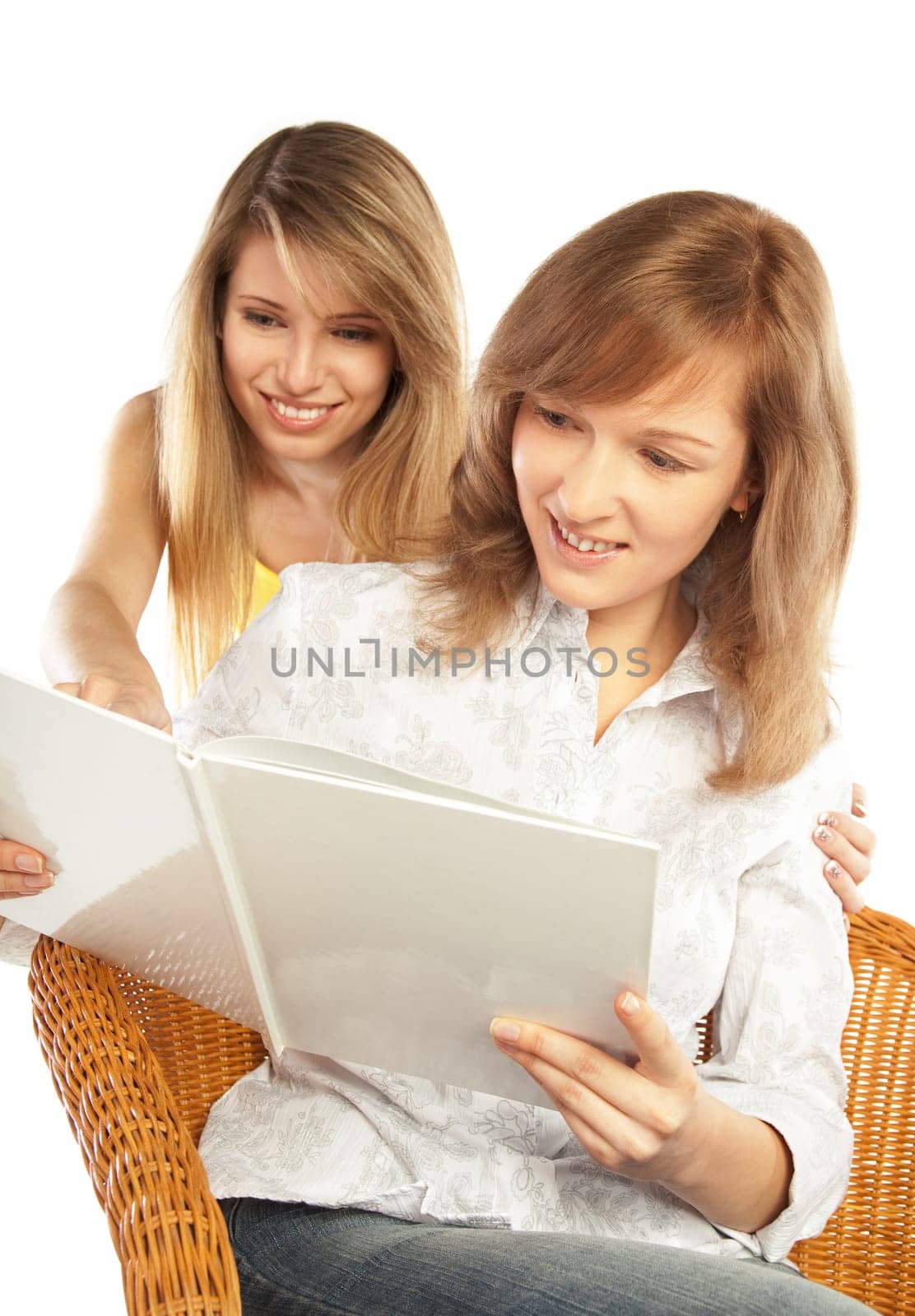 Two smiling pretty blond girls reading one book  isolated on white background