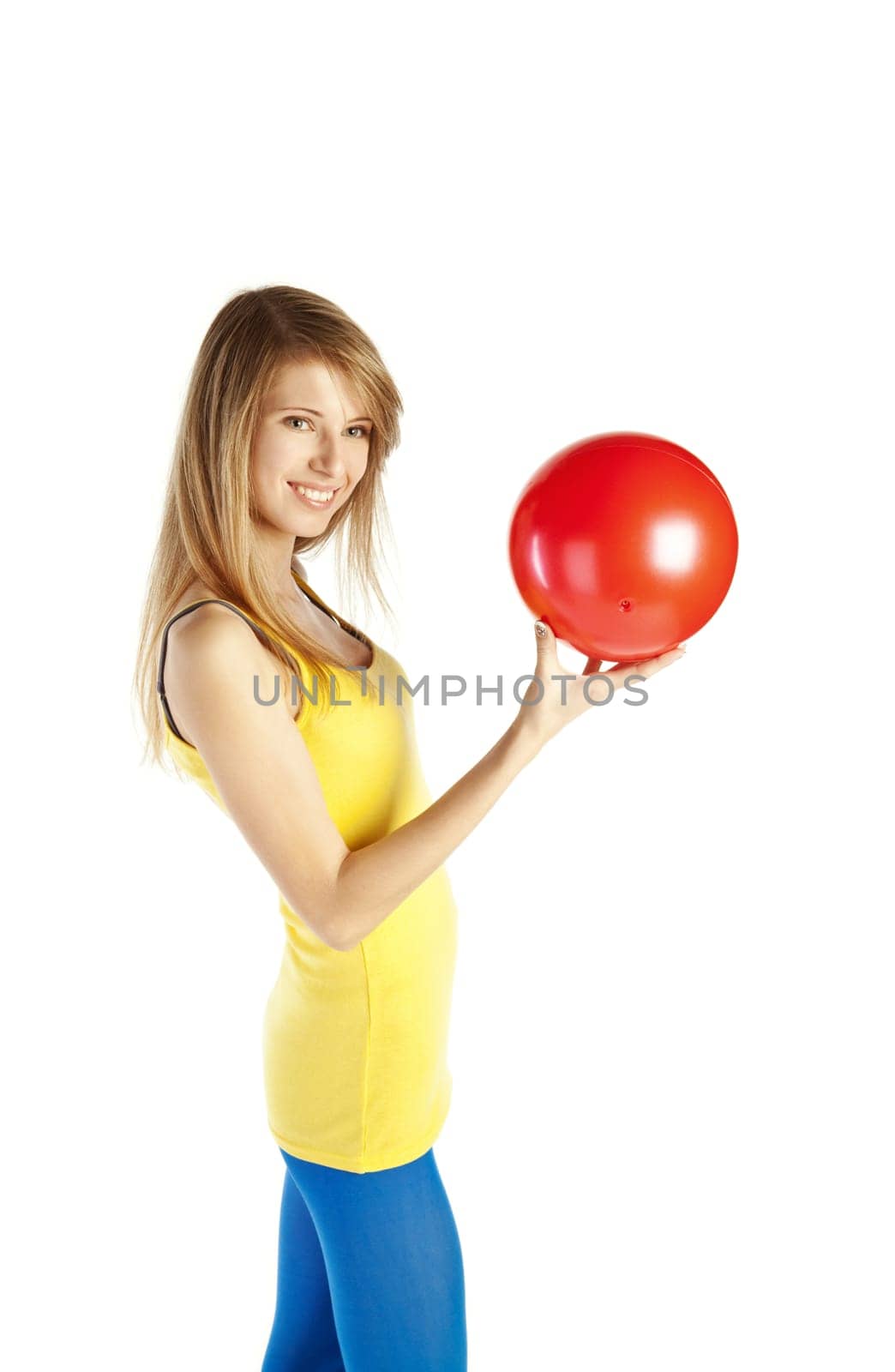 Young happy blond woman standing on tiptoe and holding red ball