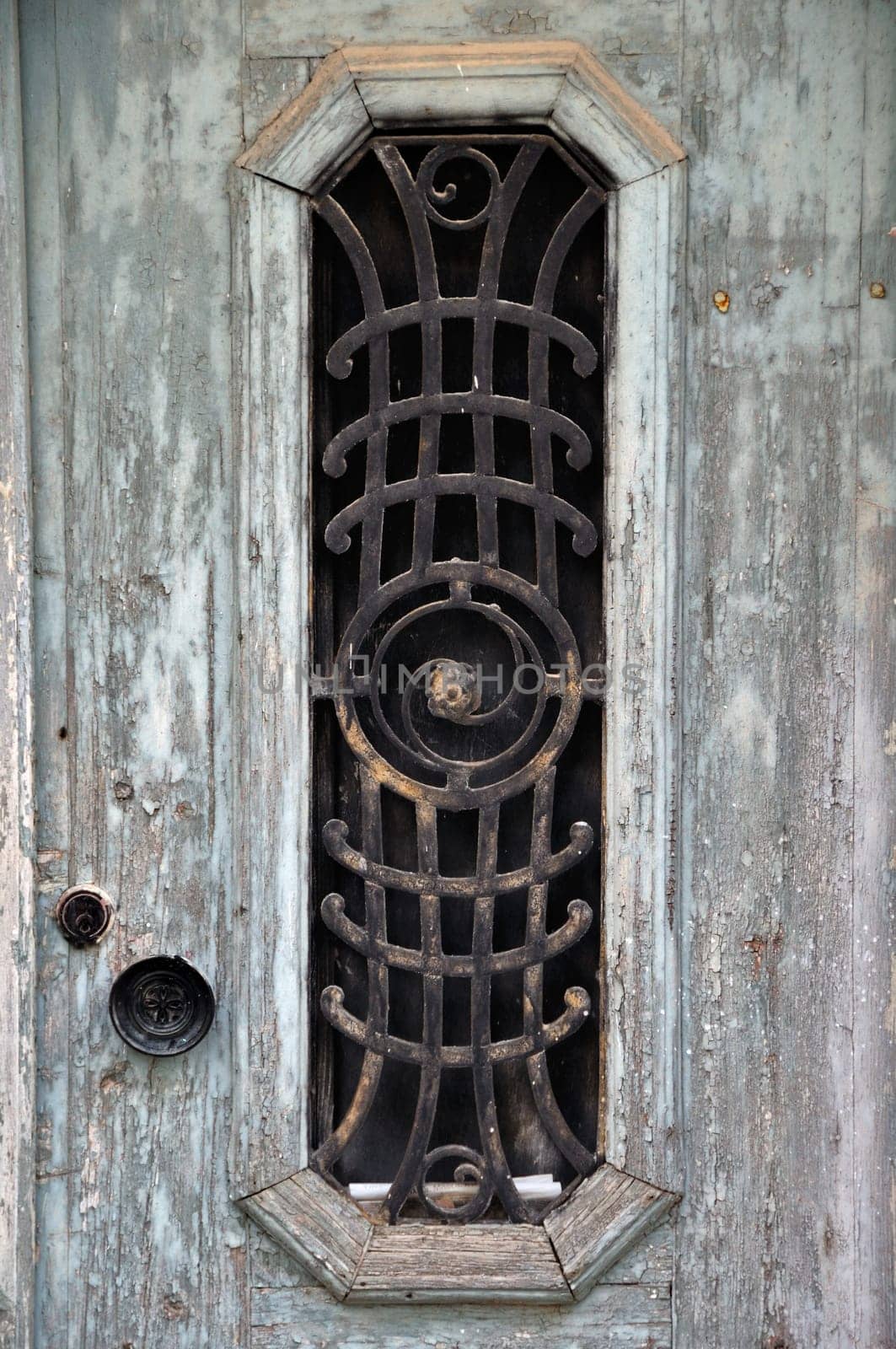 Weathered wooden door with peeling paint and vintage metalwork pattern.