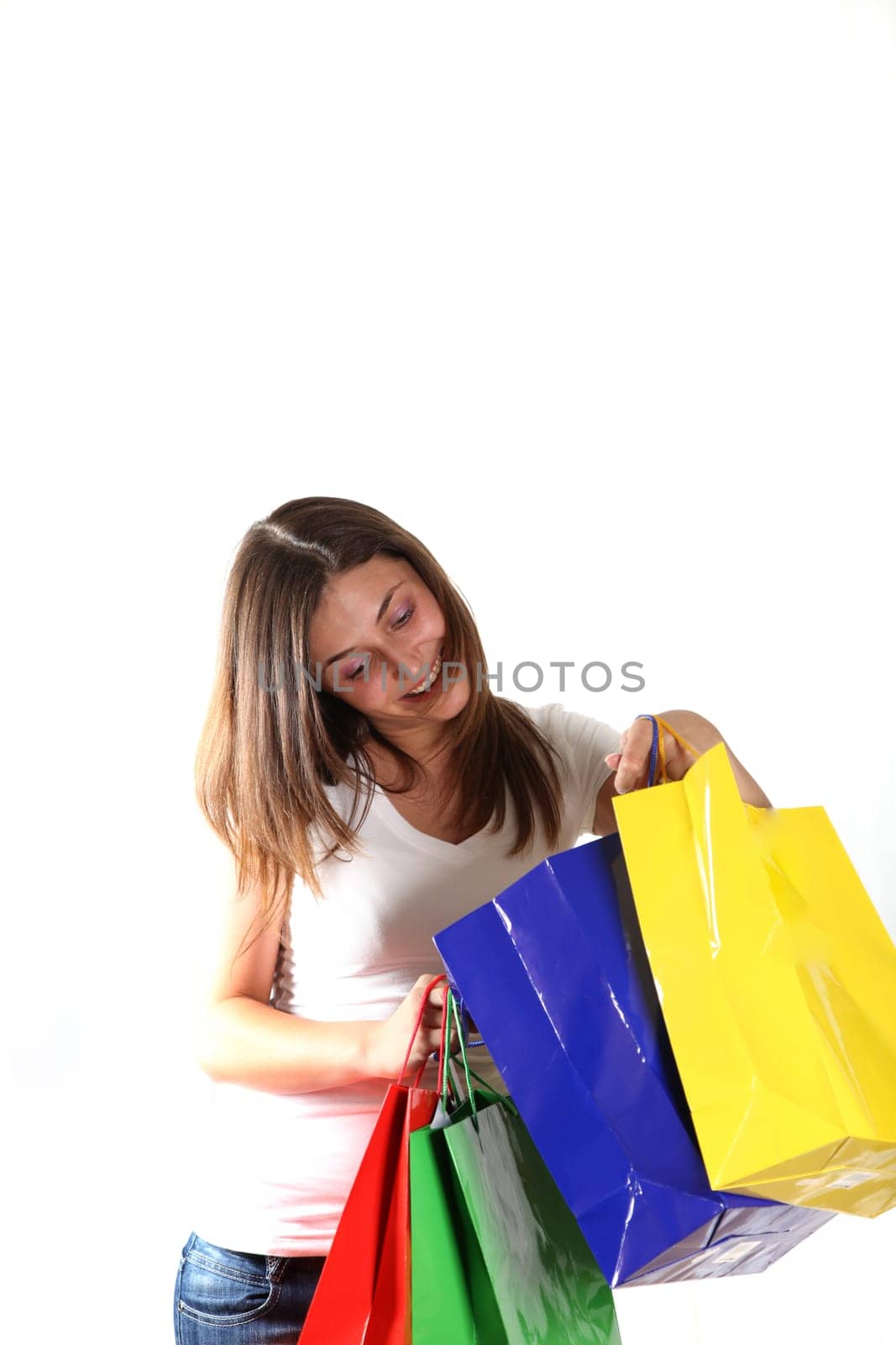 Young woman shopping. She looks happily in the colorful bags against a white background
