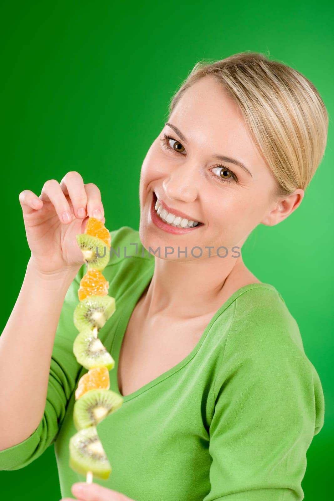 Healthy lifestyle - woman eating kiwi and orange on stick