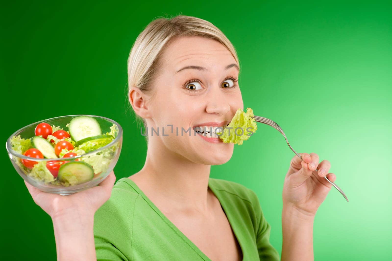 Healthy lifestyle - woman holding vegetable salad on green background