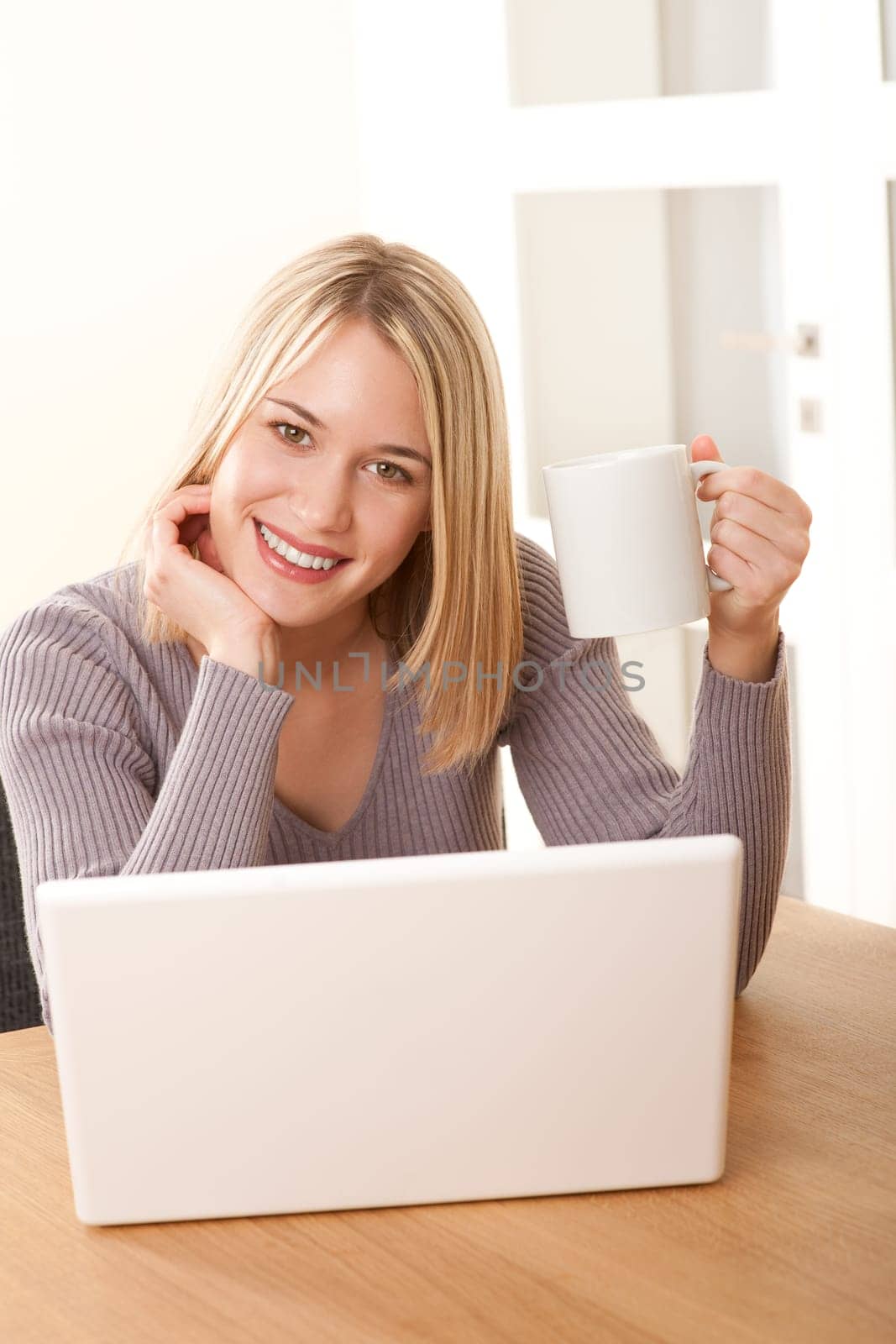 Blond woman with white mug and laptop