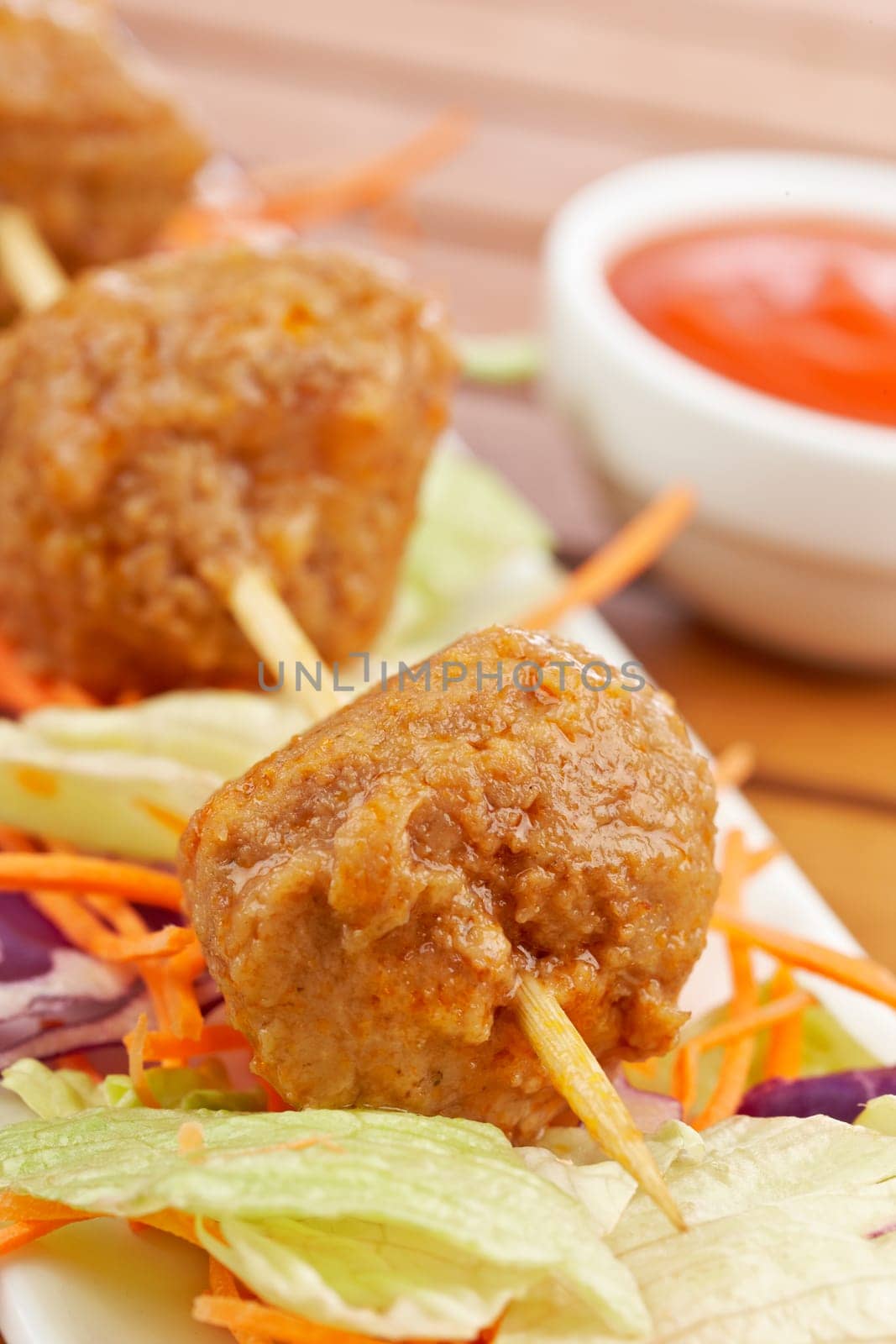 Meatballs skewer, with salad and tomato sauce, on wooden background