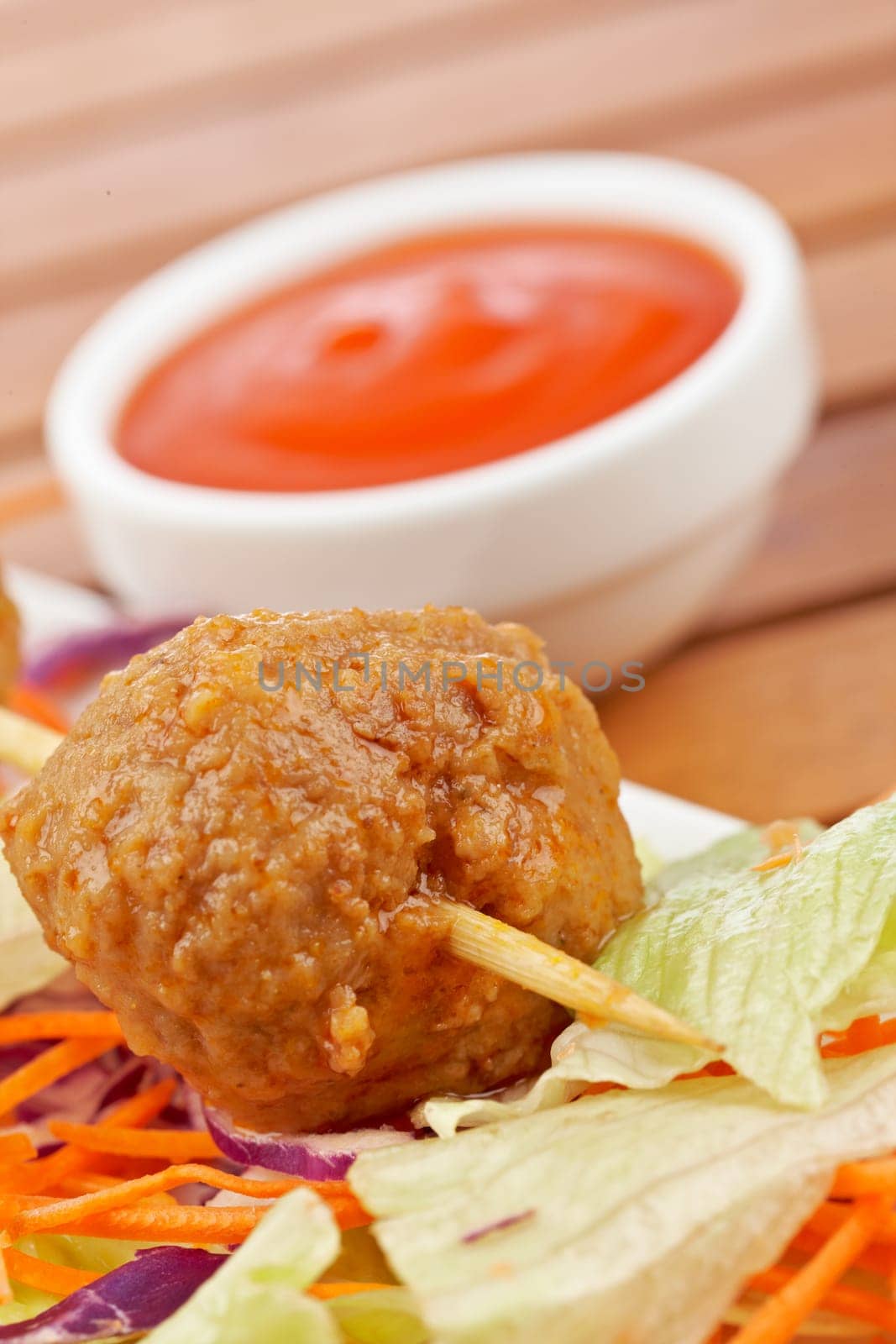 Meatballs skewer, with salad and tomato sauce, on wooden background