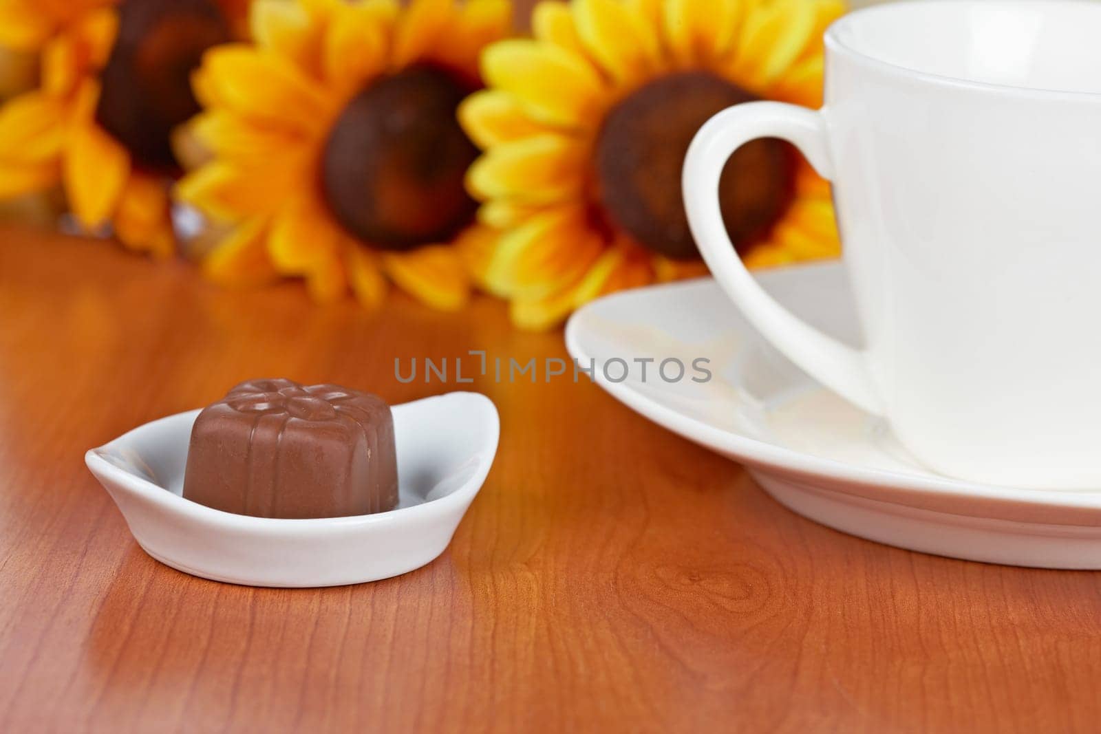 Coffee with chocolate candies and flowers on wooden background