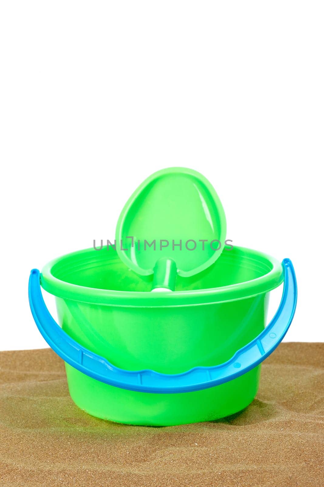 Bucket full and shovel on the sand with copy space on a white background. Shallow depth of field