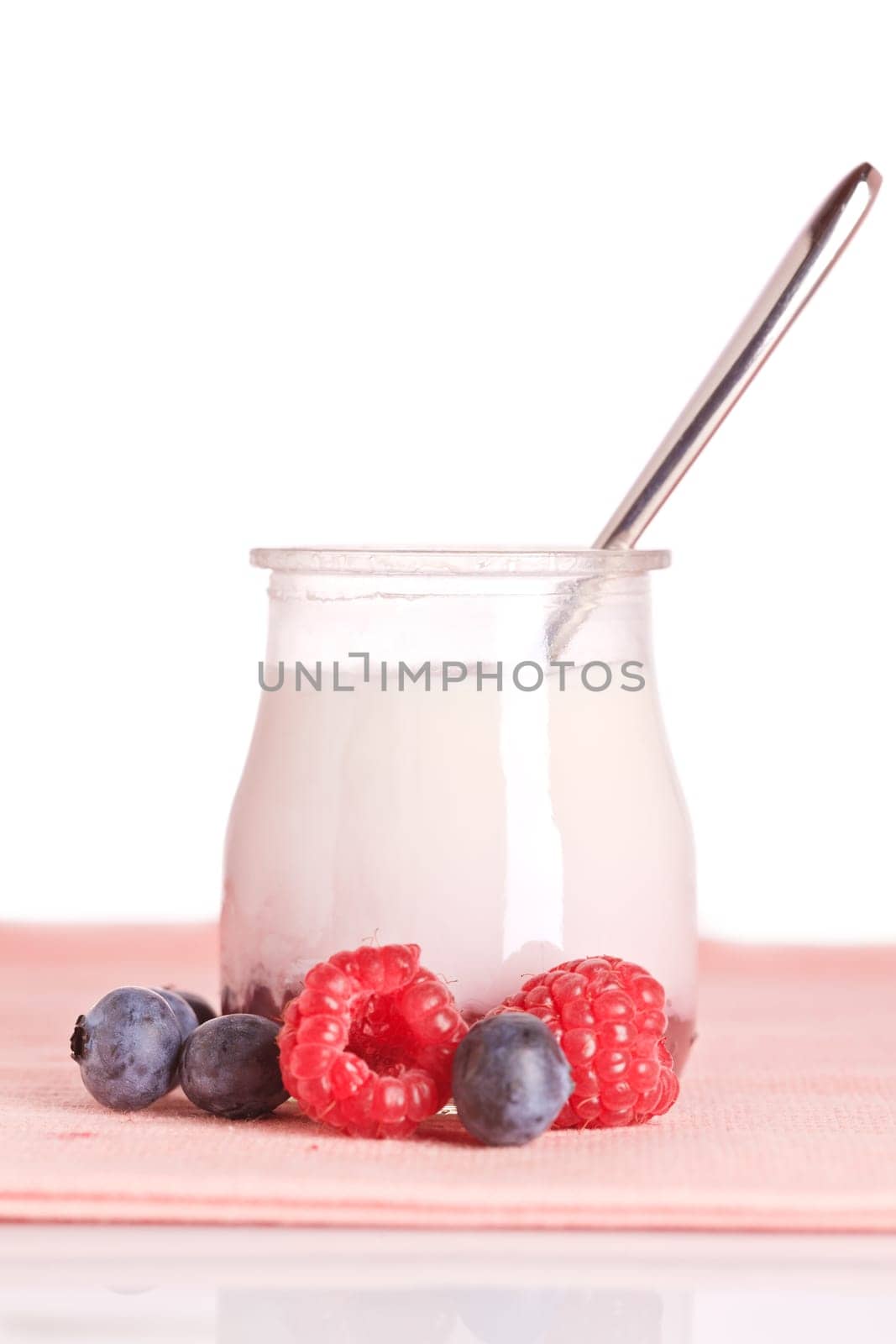 Delicious glass yogurt with a spoon and fresh raspberries and blueberries. Shallow depth of field