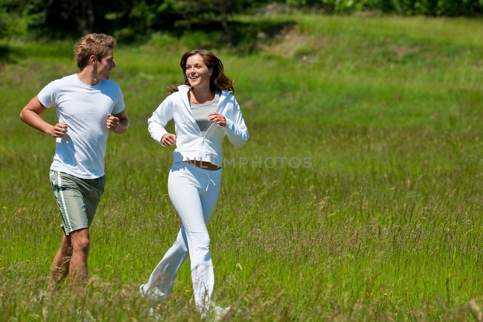 Young couple jogging outdoors in spring nature on sunny day