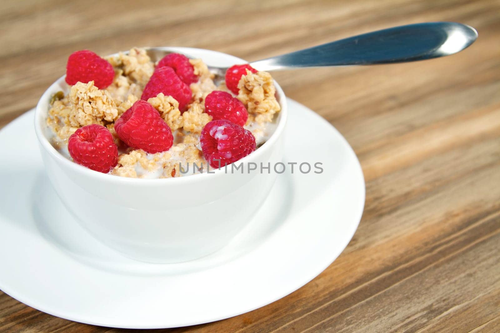 Fresh morning bowl of granola and raspberries with milk