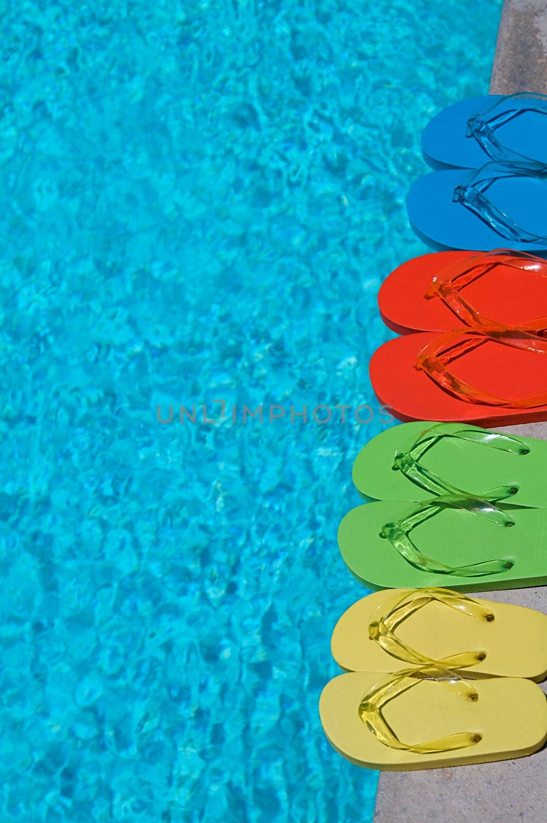 Colored flipflops of a family of four by the swimming pool