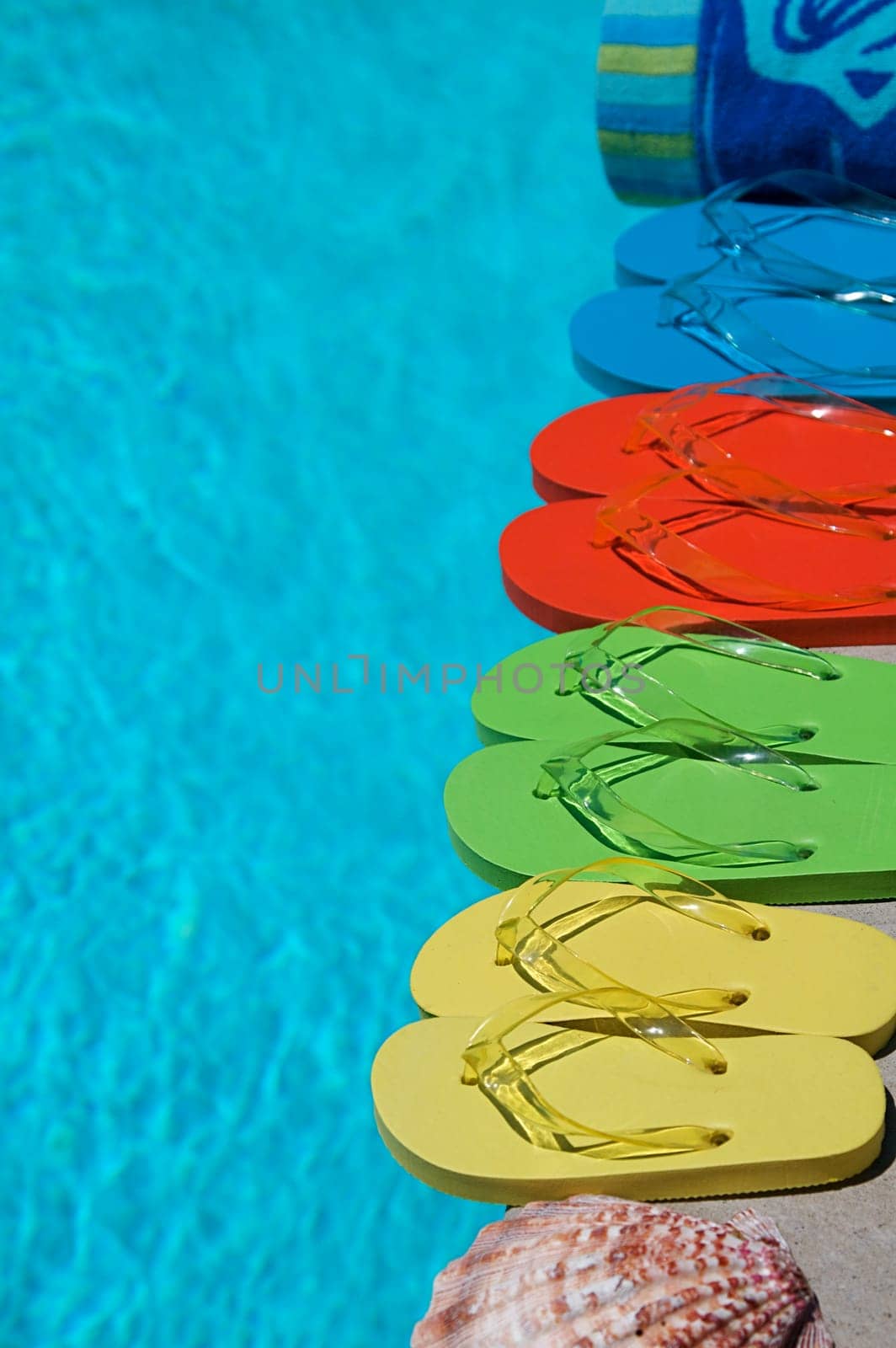 Colored flipflops of a family of four by the swimming pool
