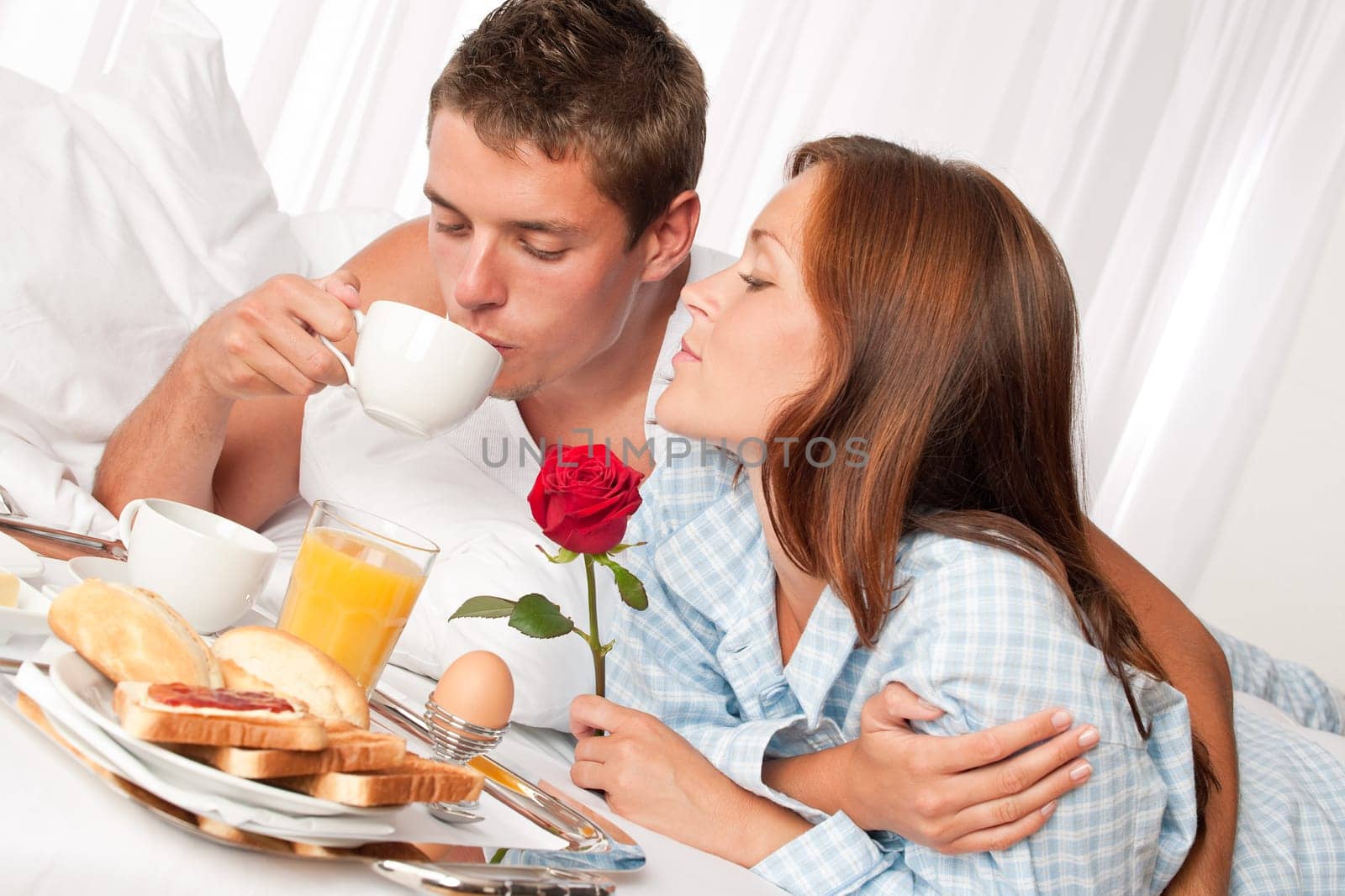 Happy man and woman having luxury hotel breakfast in bed together