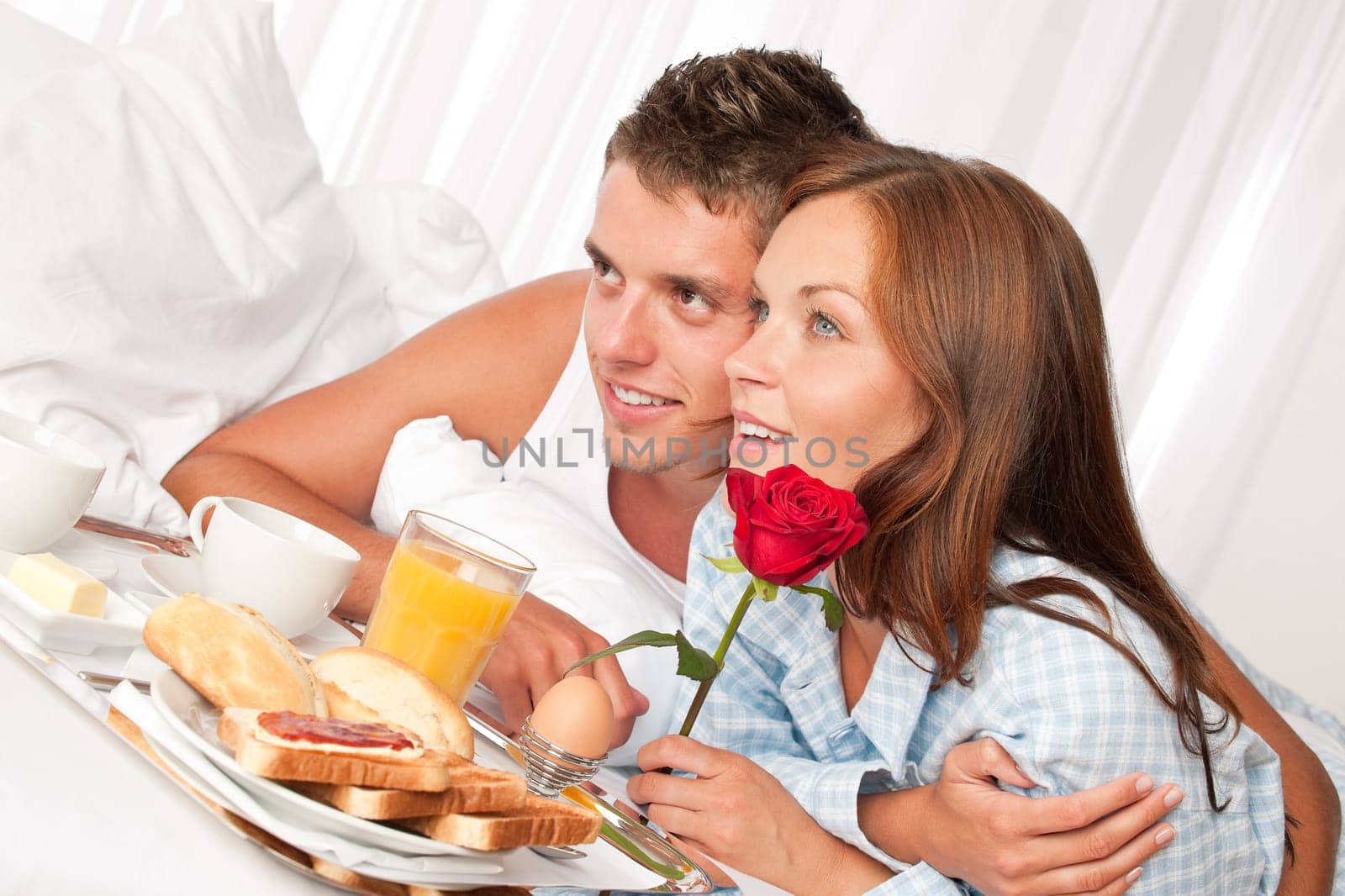 Happy man and woman having luxury hotel breakfast in bed together