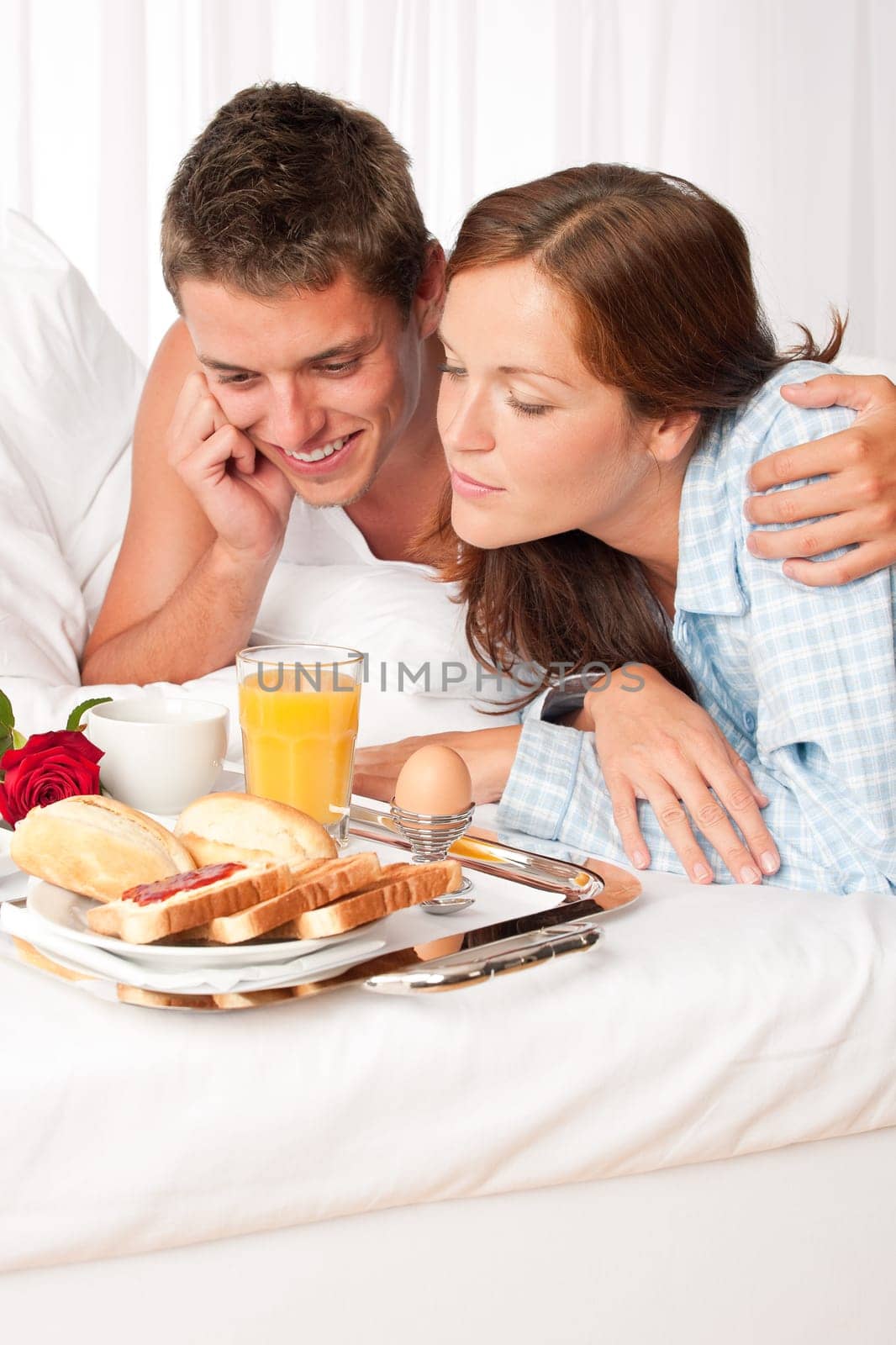 Happy man and woman having luxury hotel breakfast in bed together