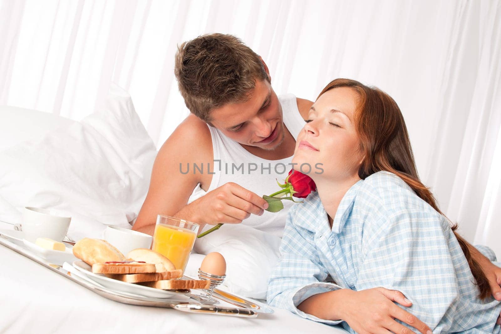 Happy man and woman having luxury hotel breakfast in bed together
