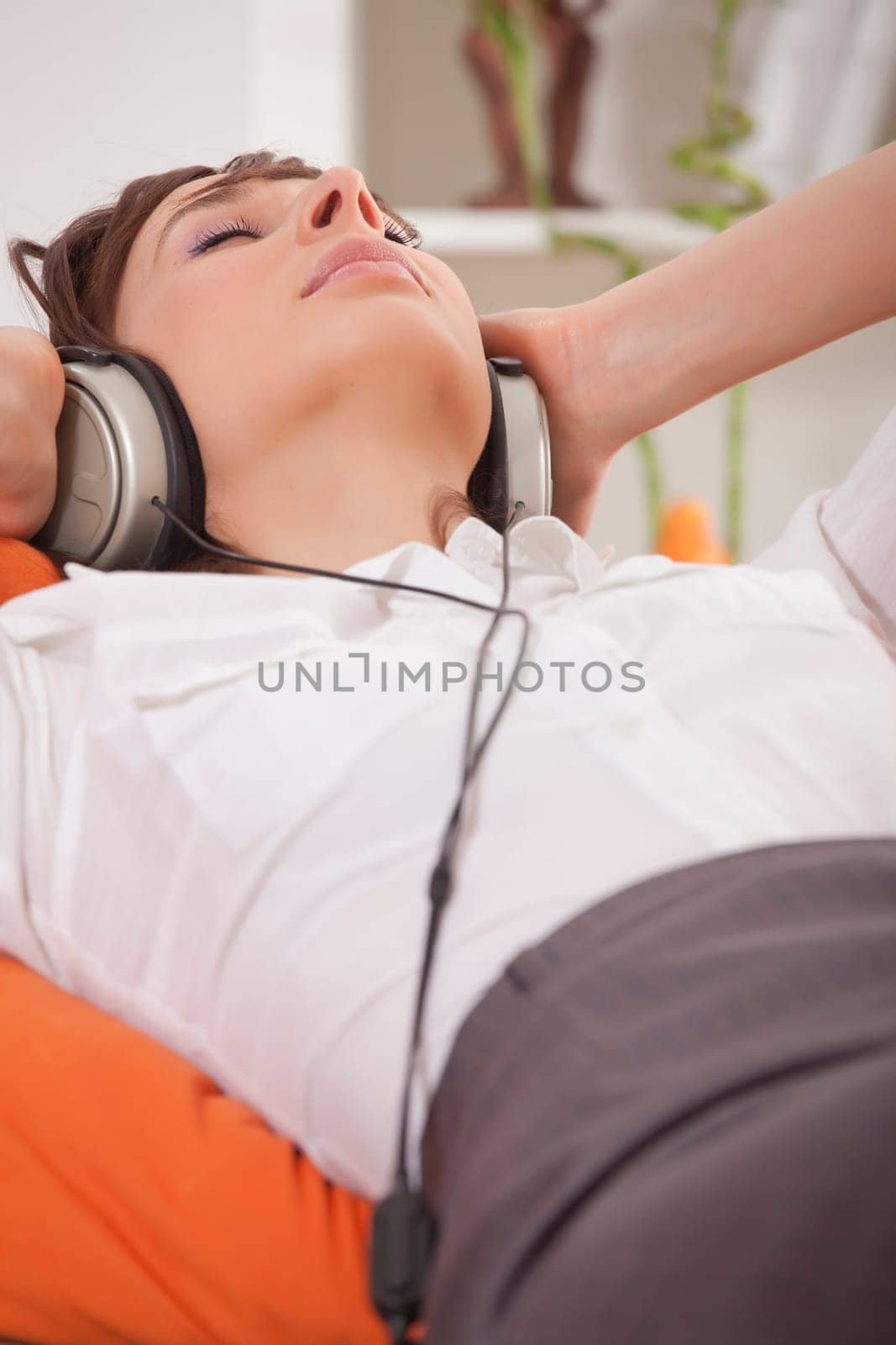woman in business suit relaxing at home and hearing music in earphones