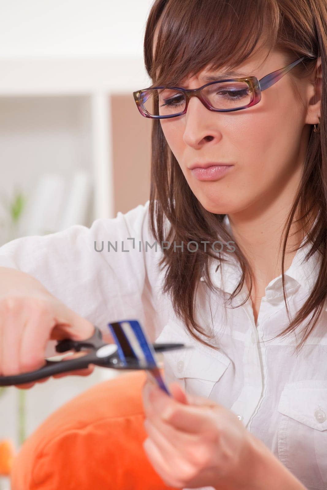 frustrated woman cuts credit card with scissors at home