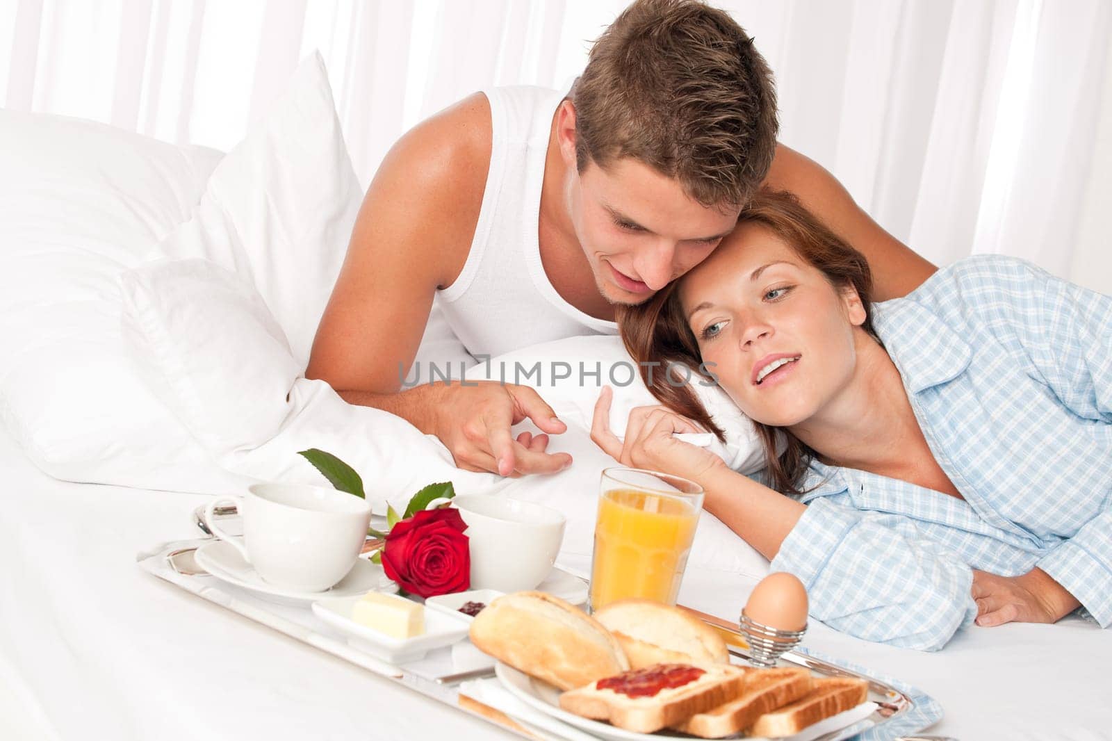 Happy man and woman having luxury hotel breakfast in bed together
