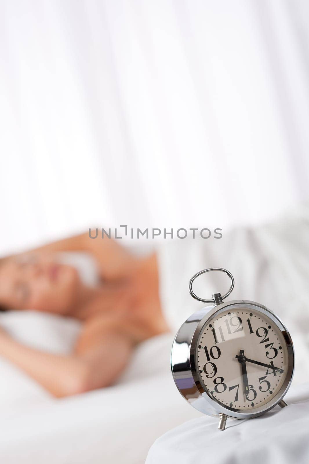 Silver alarm clock, woman in background, shallow DOF