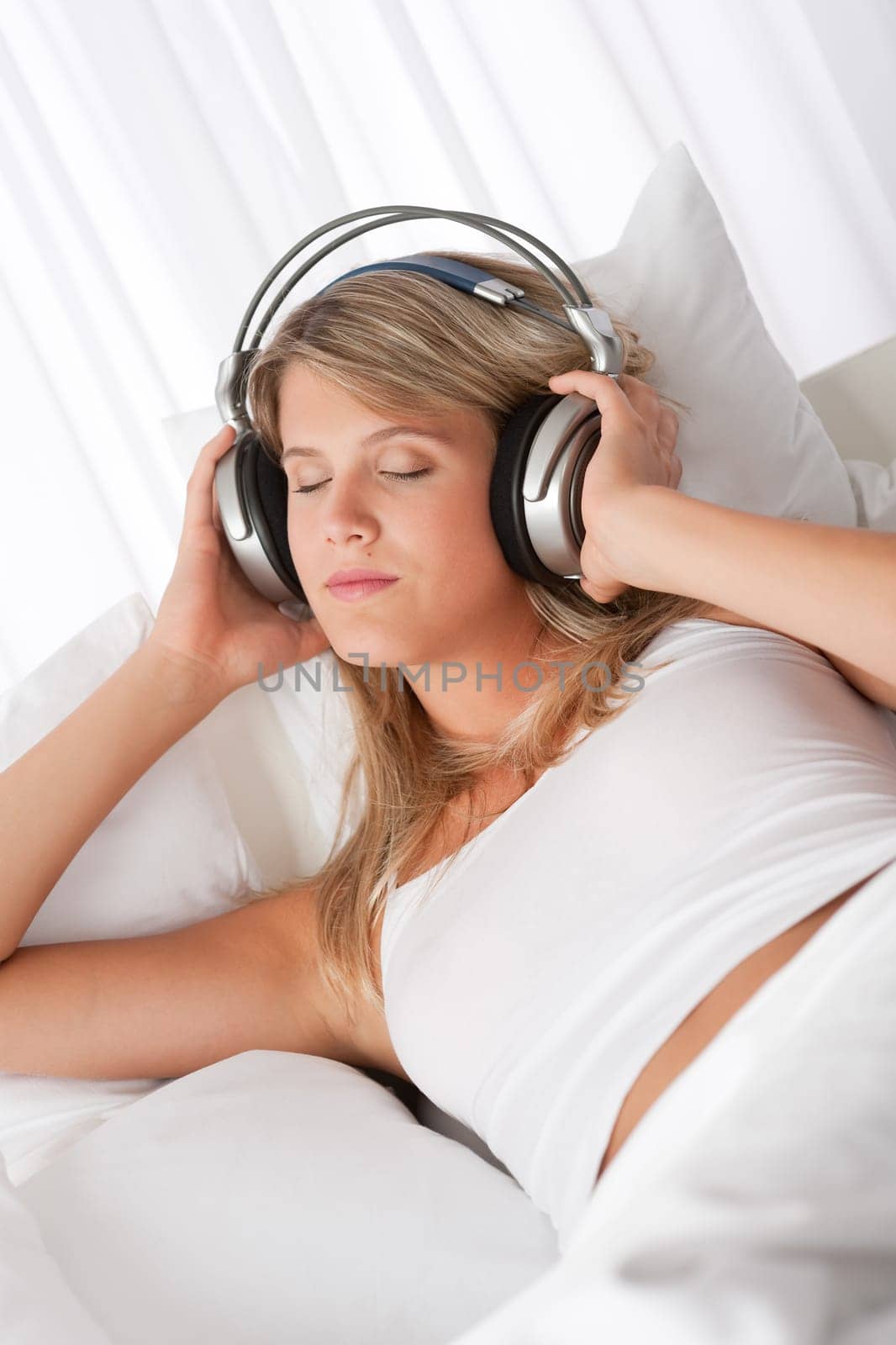 Blond woman with headphones listening to music with closed eyes
