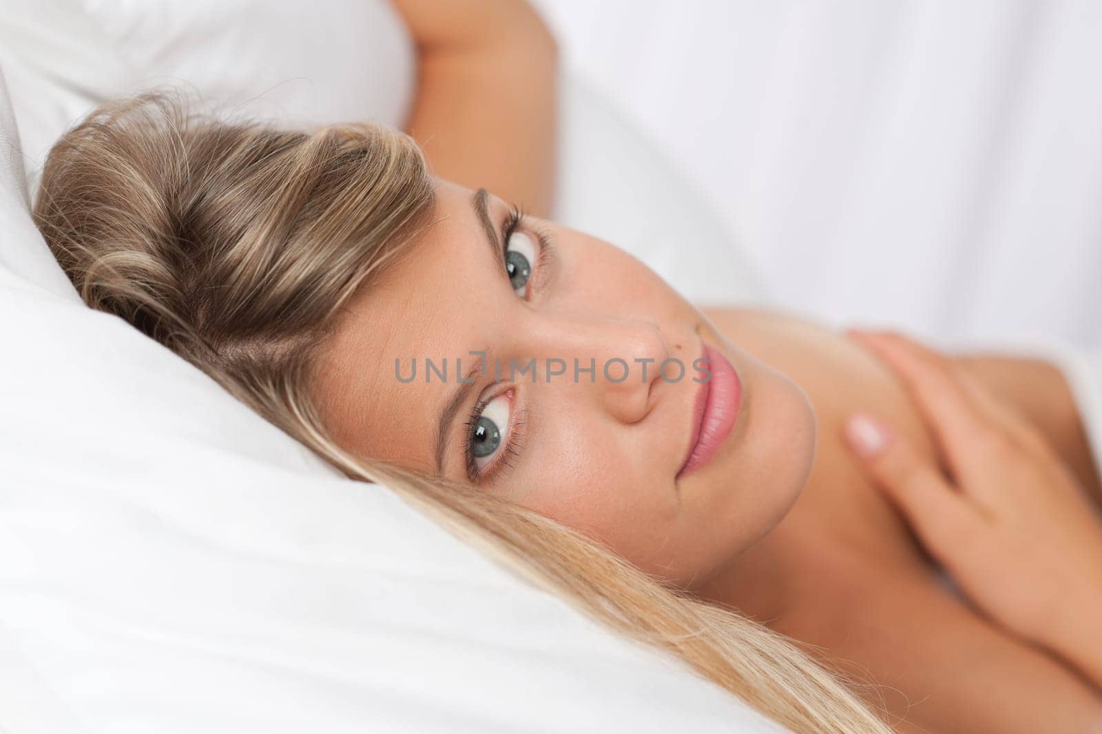 Naked blond woman lying in white bed and sleeping