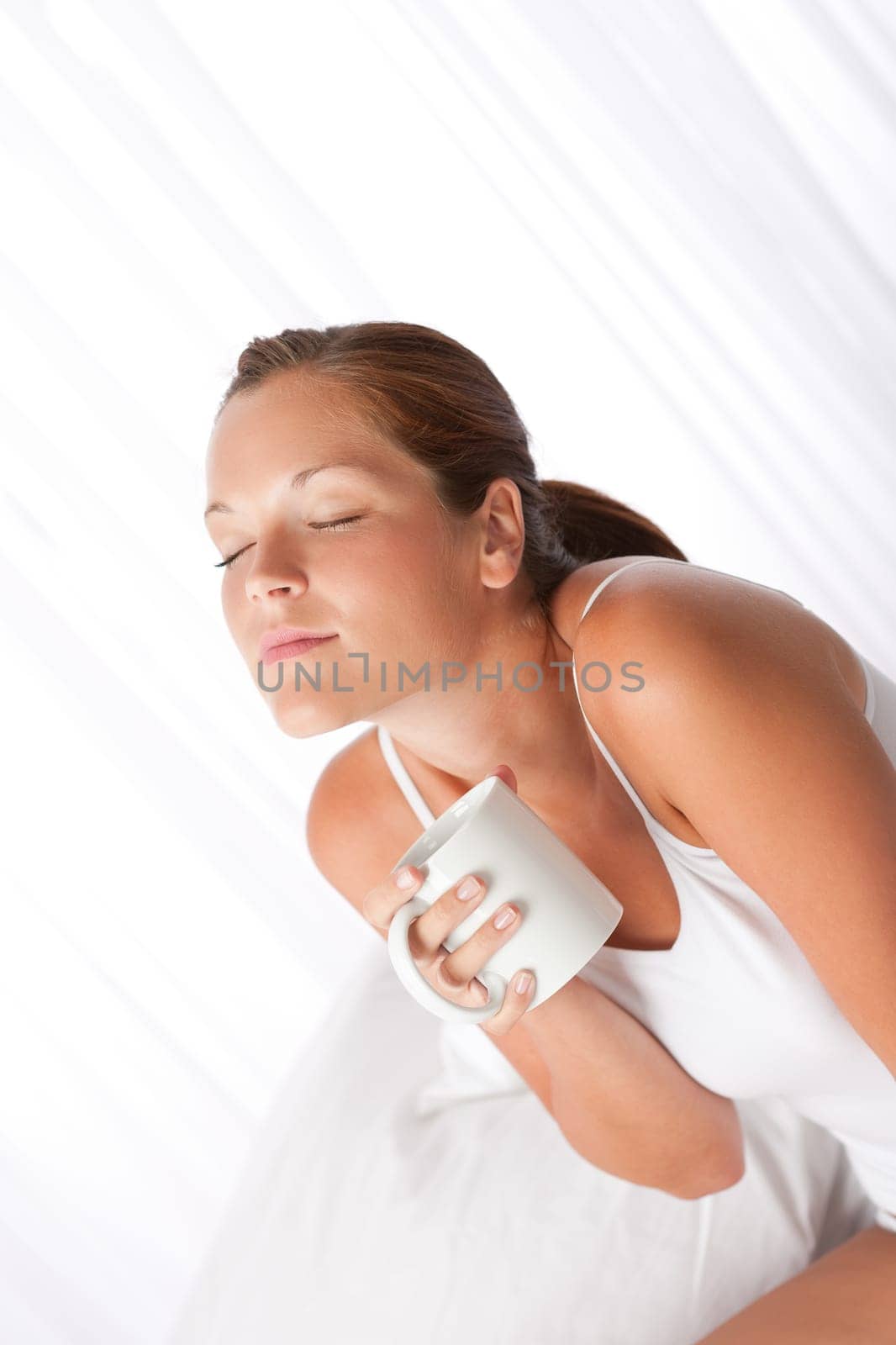 Beautiful young woman holding white cup of coffee home