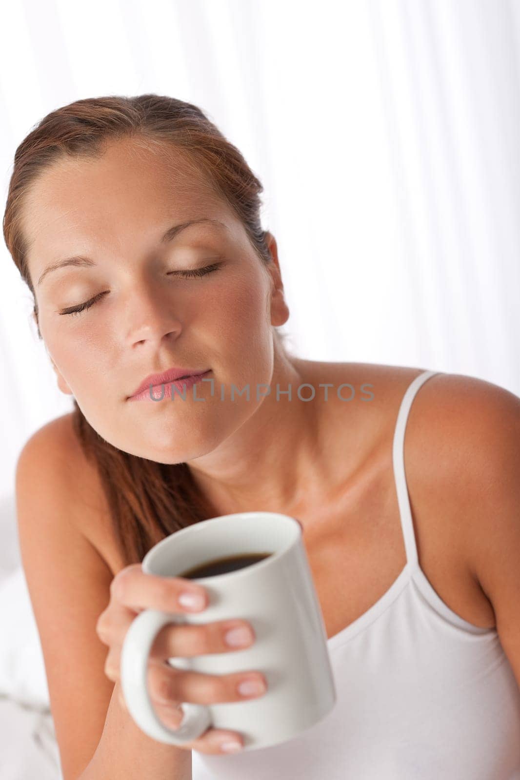 Beautiful young woman holding white cup of coffee home